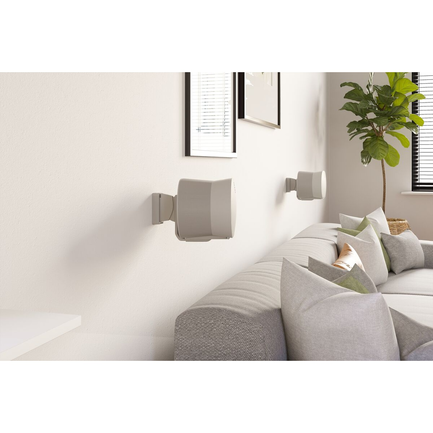 Gray speakers on a white wall above a sofa with cushions. Plant in a basket.