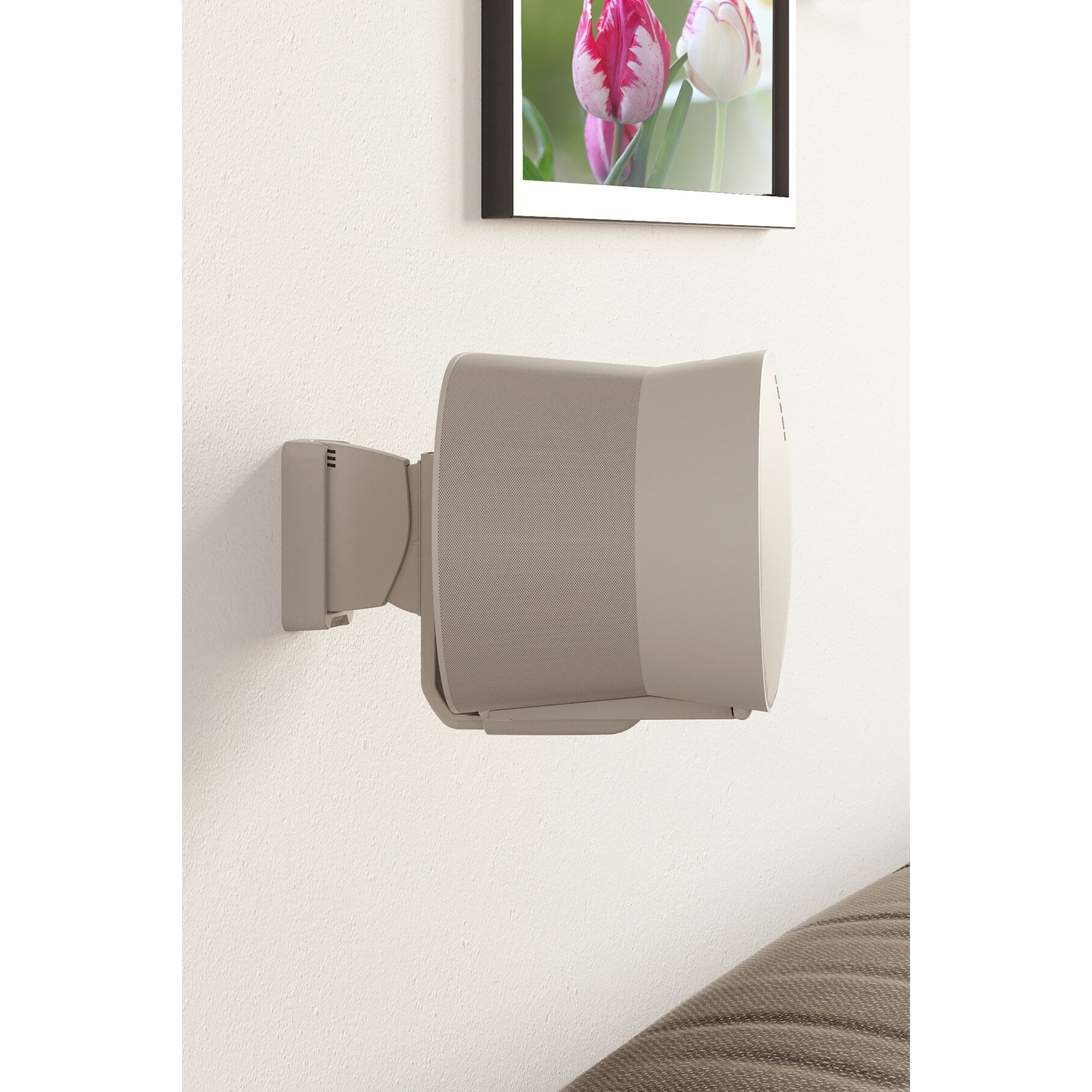 A beige speaker mounted on a white wall, with a picture of tulips beside it.