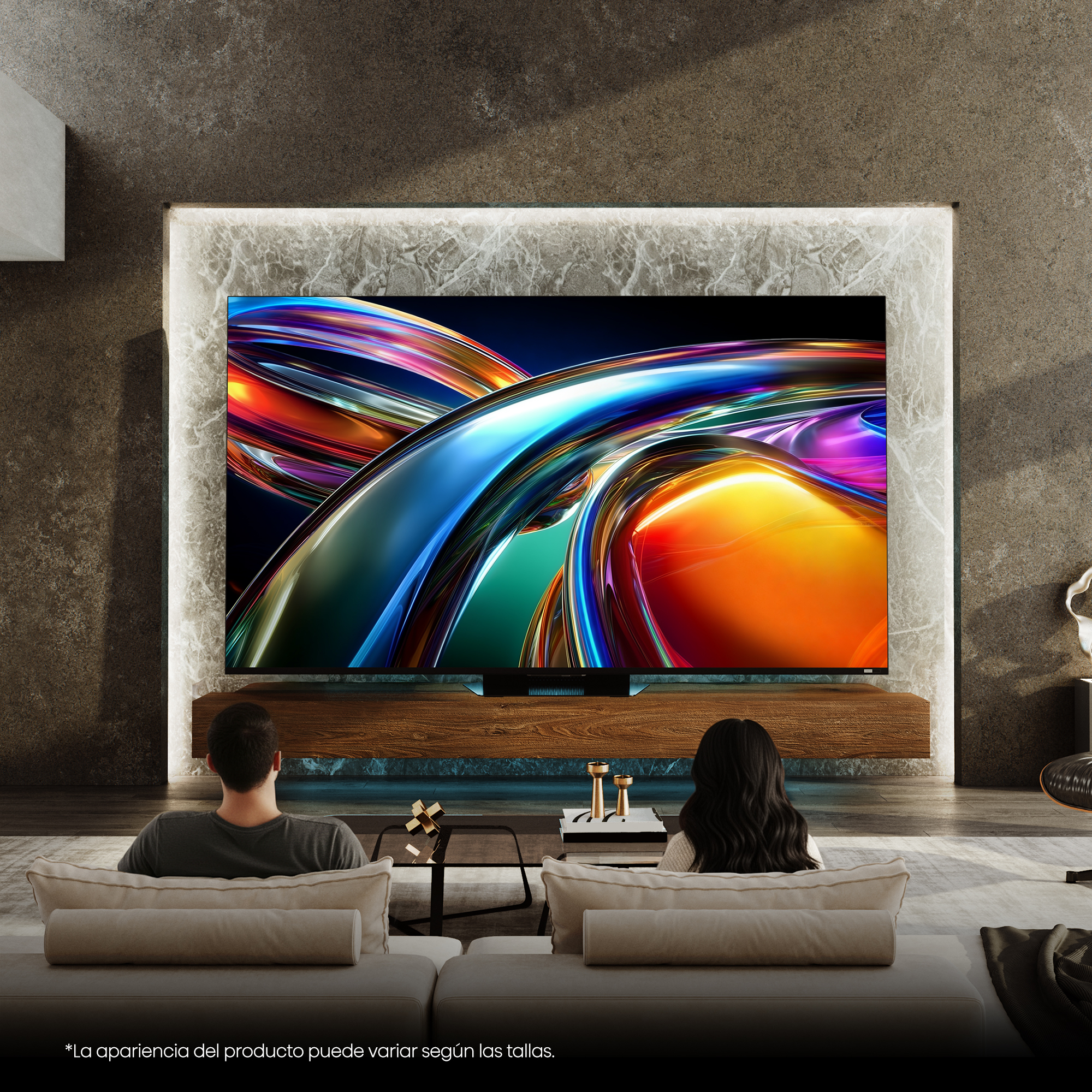 Una pareja sentada en sofás mira un gran televisor con arte abstracto colorido.