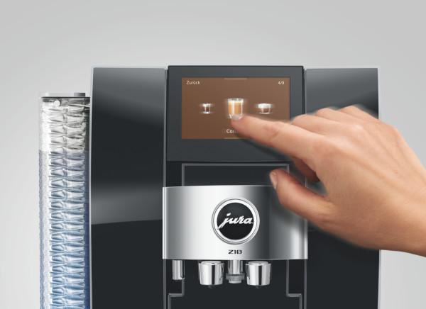 Eine Hand berührt den Bildschirm einer Kaffeemaschine, die Cappuccino anzeigt.