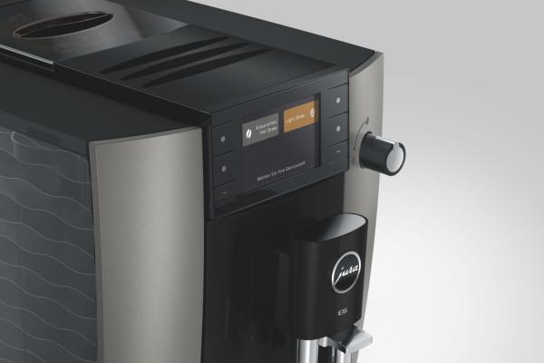 Eine moderne Kaffeevollautomat-Maschine mit Touchscreen-Display und Drehknopf.
