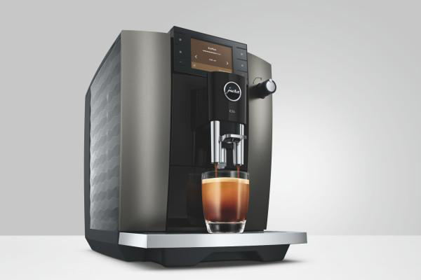 Eine Kaffeemaschine brüht Kaffee in ein Glas auf einem Tisch.