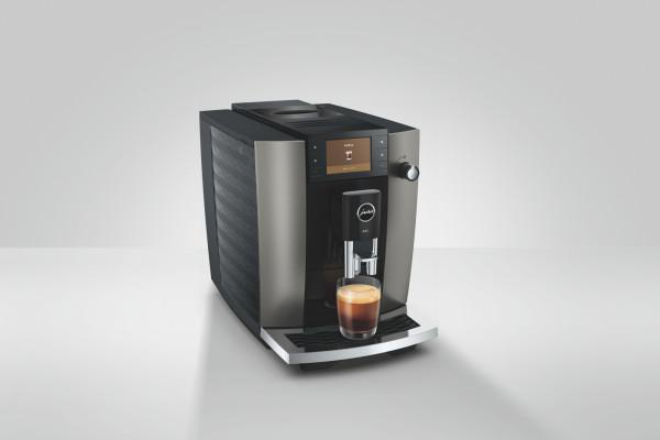 Eine JURA Kaffeemaschine mit einem Glas Espresso darauf, auf weißem Hintergrund.