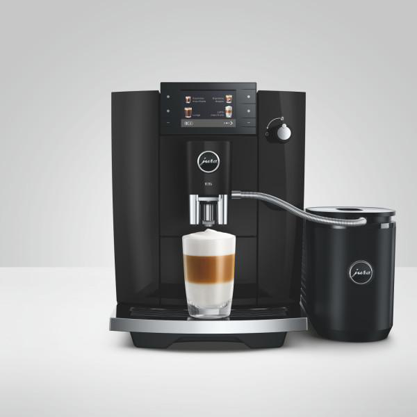 Schwarze Kaffeemaschine mit Milchbehälter und Glas Latte Macchiato.