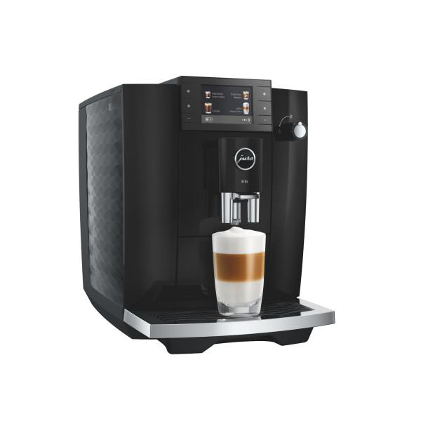 Schwarze Kaffeemaschine mit einem Glas Latte Macchiato.
