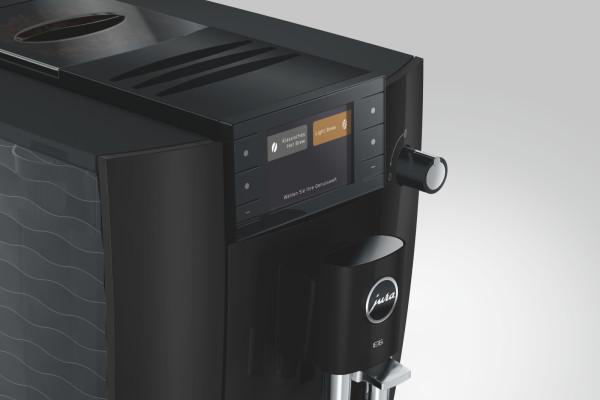 Schwarze Kaffeemaschine mit Touchscreen, Drehregler und Kaffeebohnenbehälter.