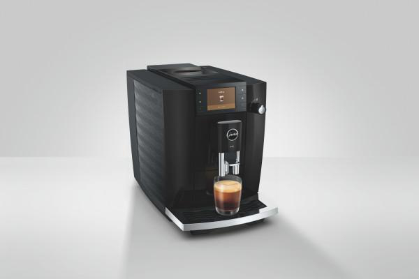 Schwarze Kaffeemaschine brüht einen Espresso in ein Glas auf einer Arbeitsplatte.