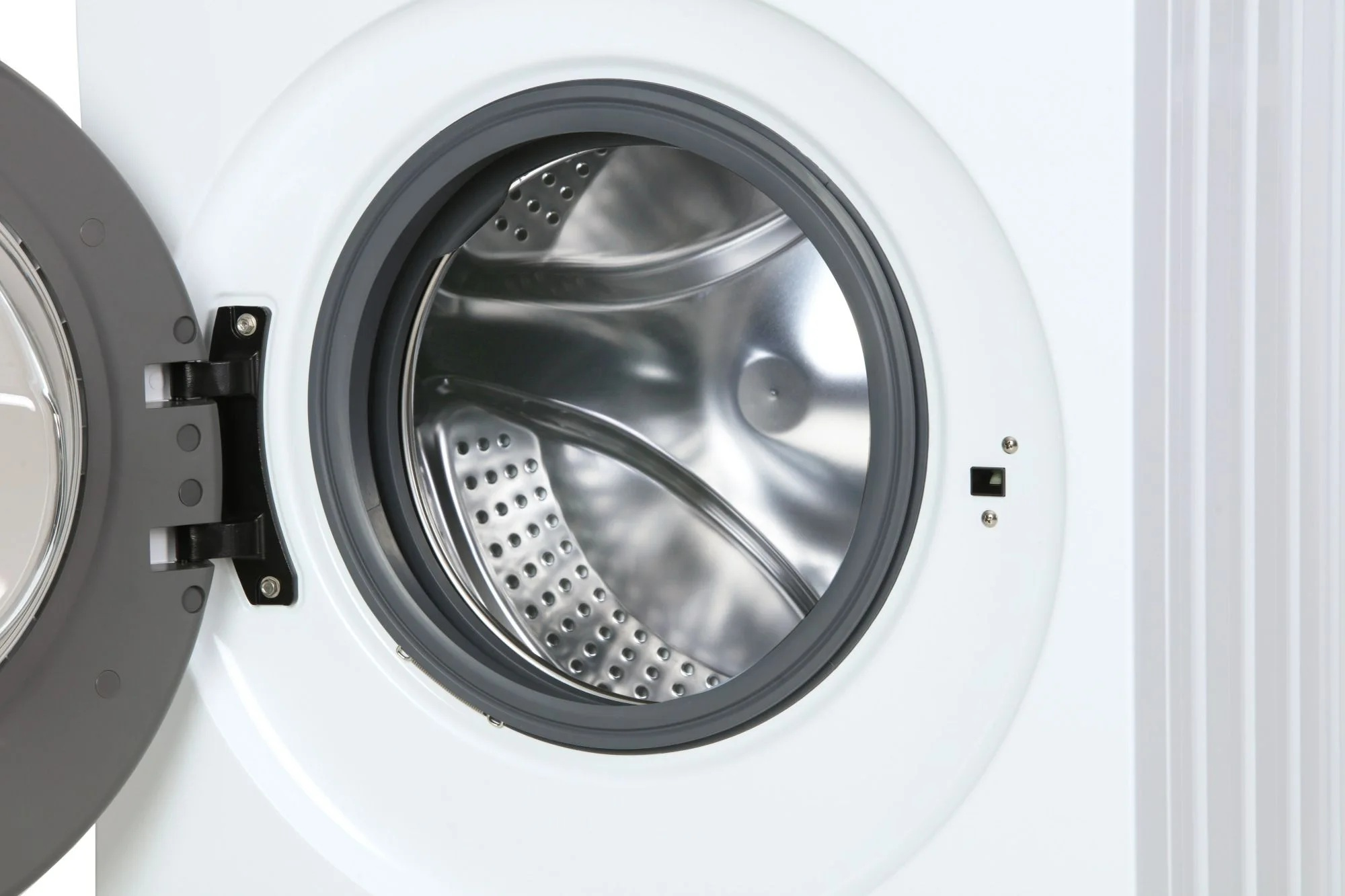 Biała pralka z otwartymi drzwiami, widok wnętrza bębna.