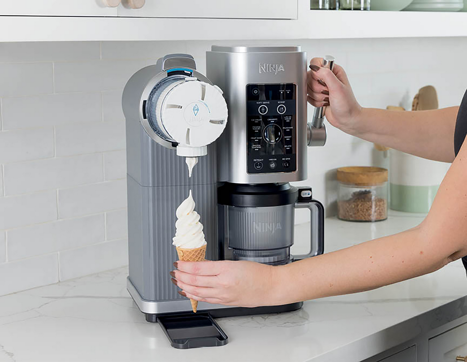 Una persona opera una máquina de helados dispensando helado suave en un cono.