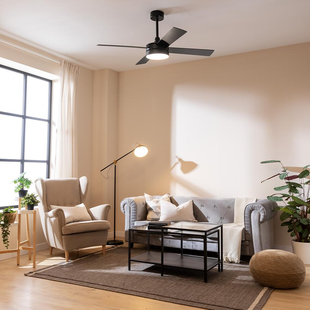 Una sala de estar con sillón, sofá, mesa de centro, lámpara y ventilador de techo.