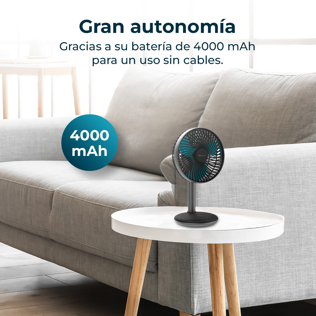 Un pequeño ventilador negro sobre una mesa auxiliar blanca delante de un sofá.