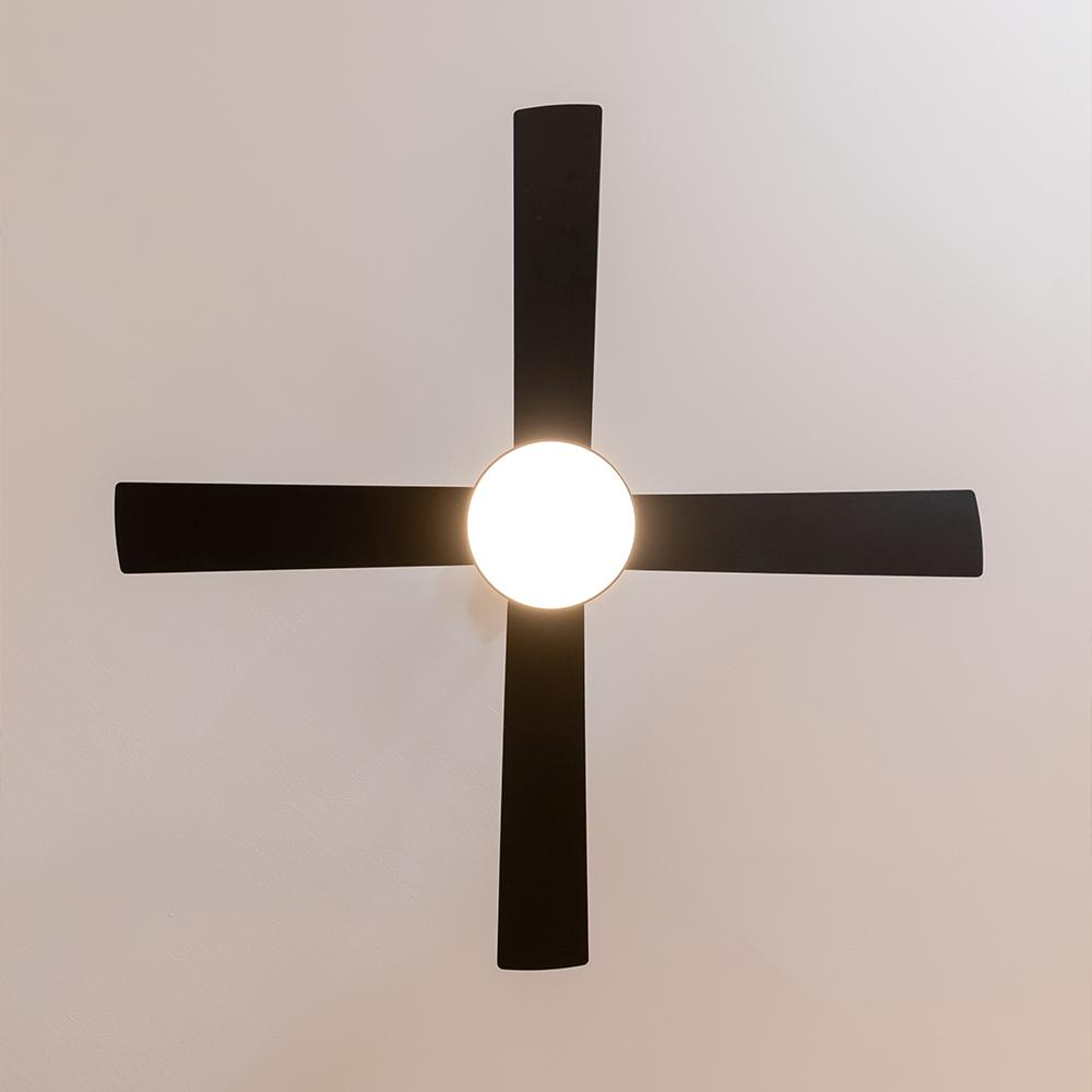 Ventilador de techo negro de cuatro aspas con luz redonda en el centro.