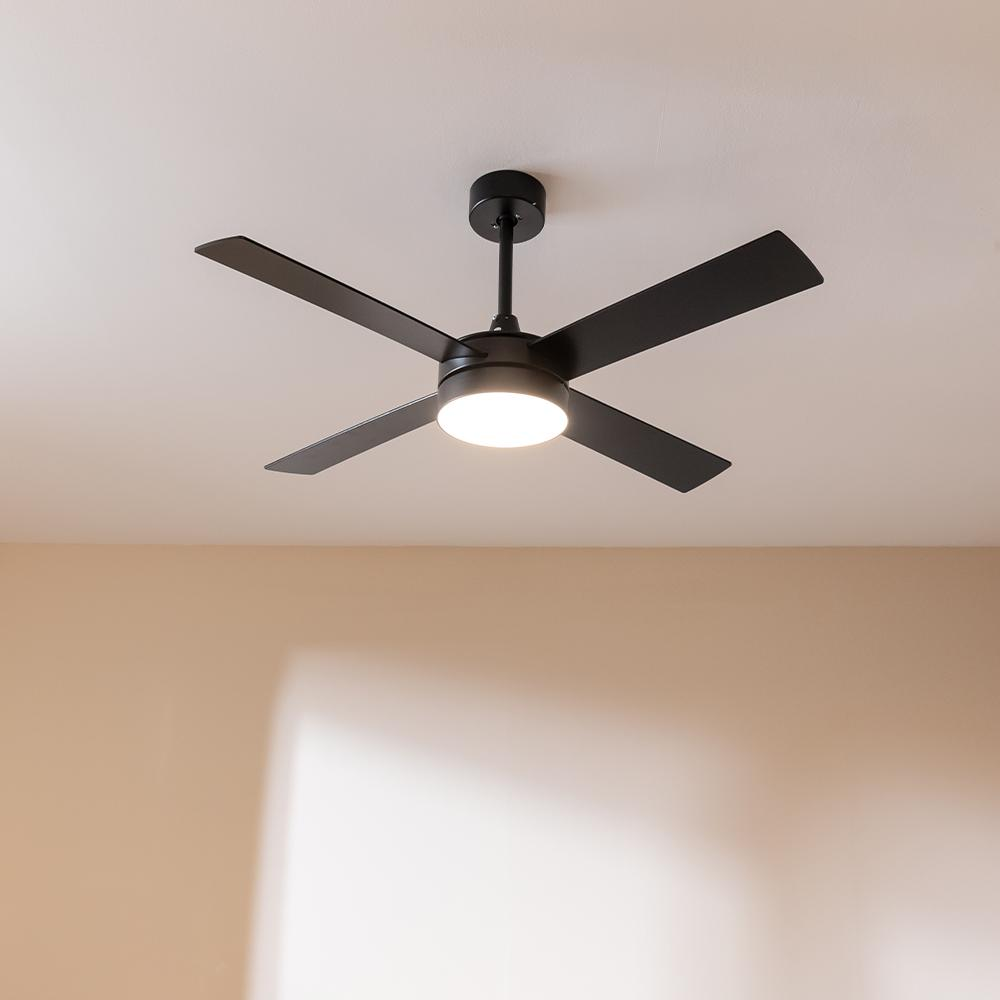 Ventilador de techo negro con luz en un techo blanco.