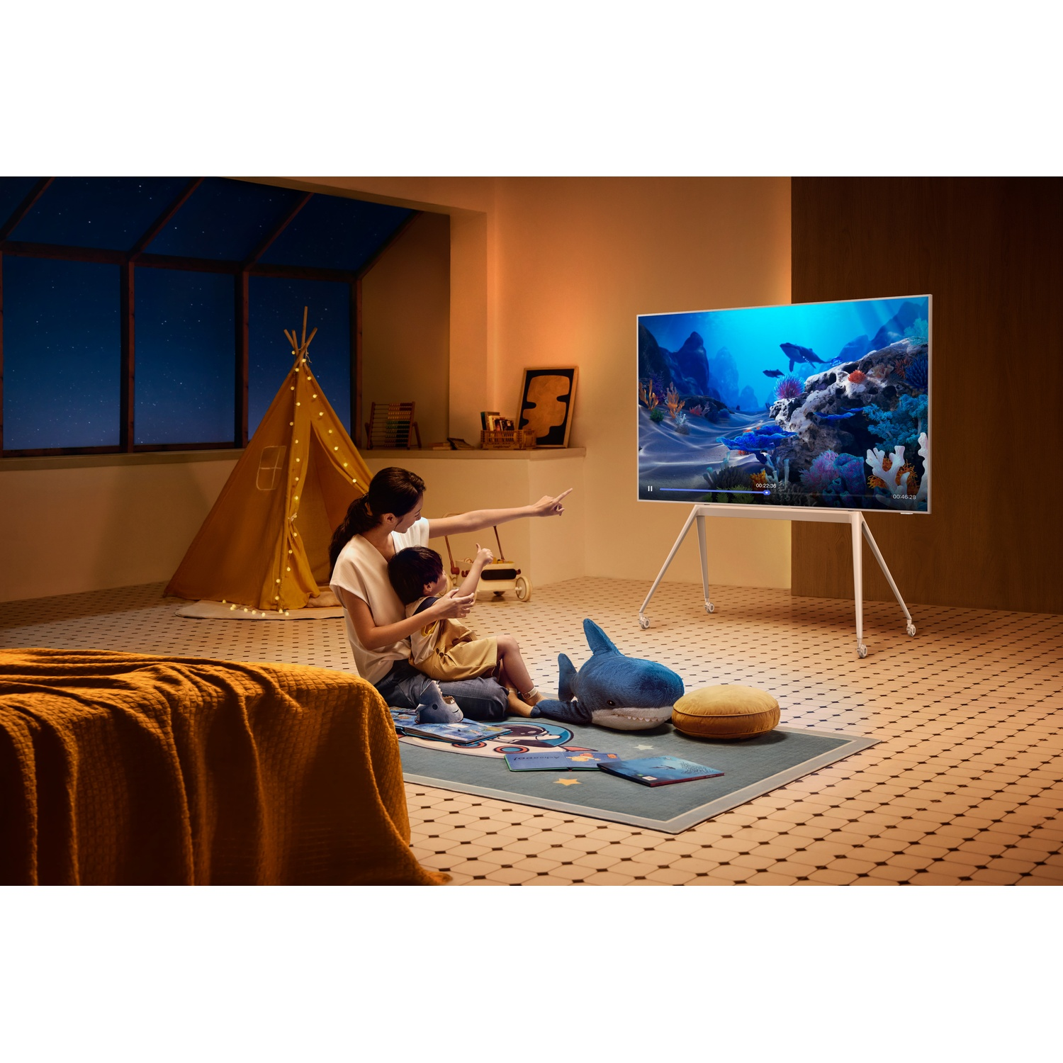 Mother and child sit on floor watching TV displaying underwater world.