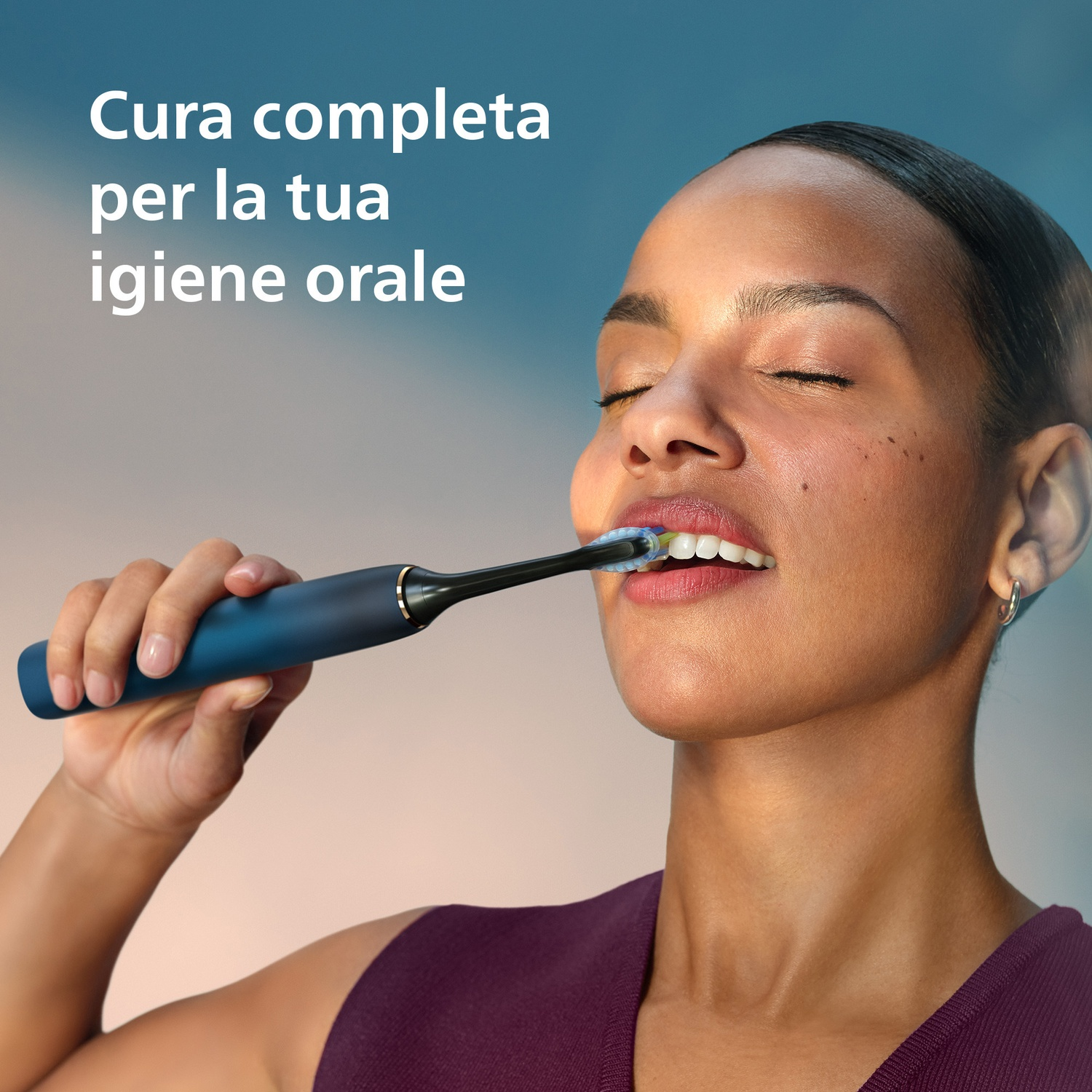 Una donna si lava i denti con uno spazzolino elettrico blu.