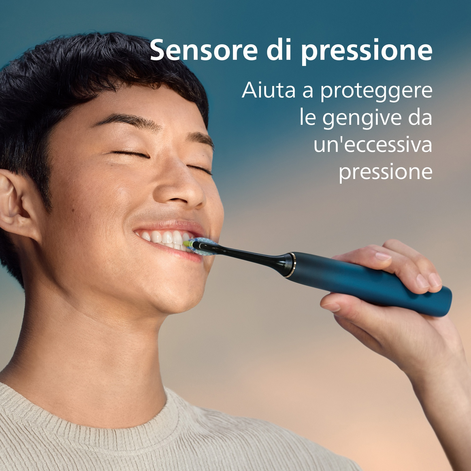 Un uomo si lava i denti con uno spazzolino elettrico blu su sfondo sfocato.