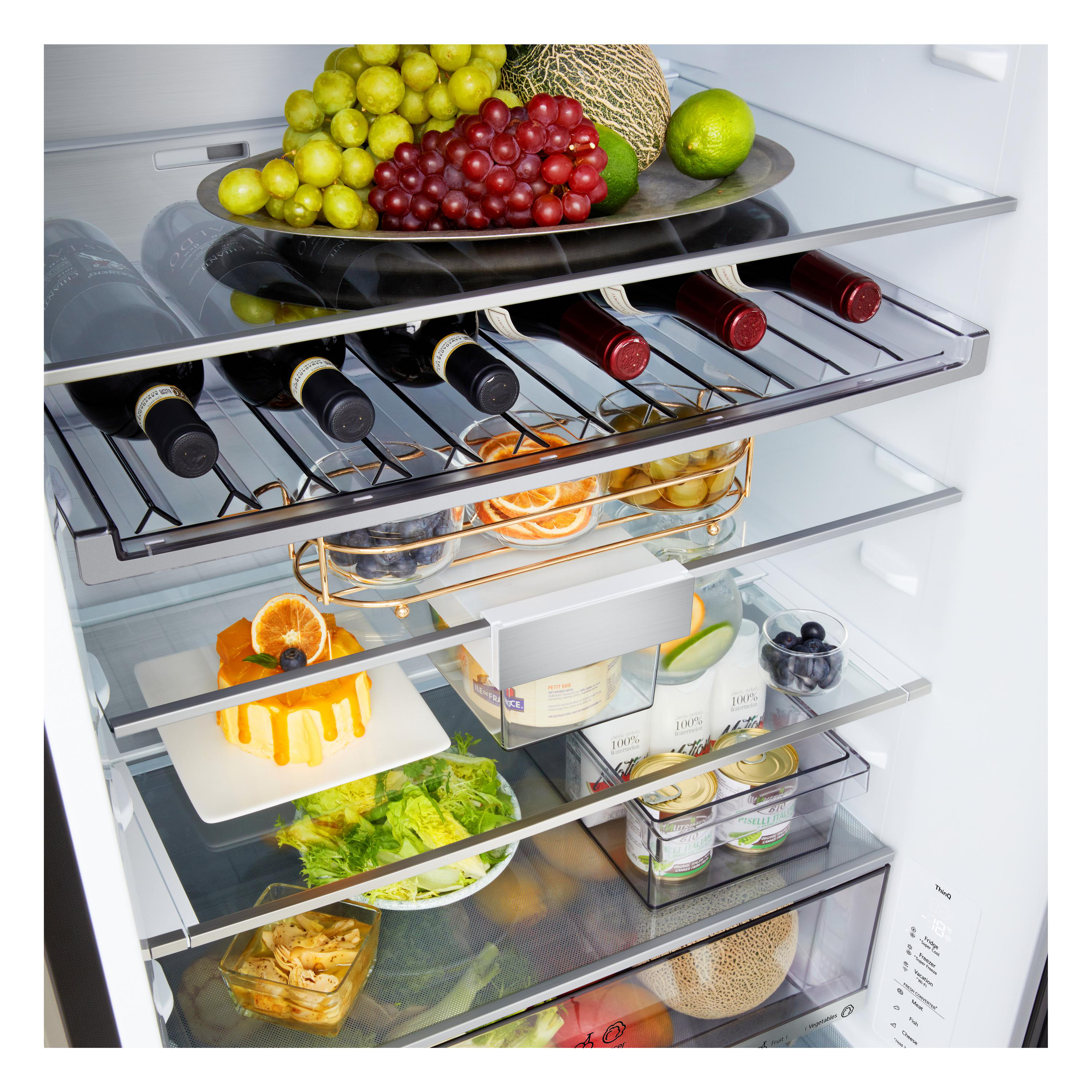Kühlschrank mit Früchten, Wein, Kuchen und Käse auf Glasböden.