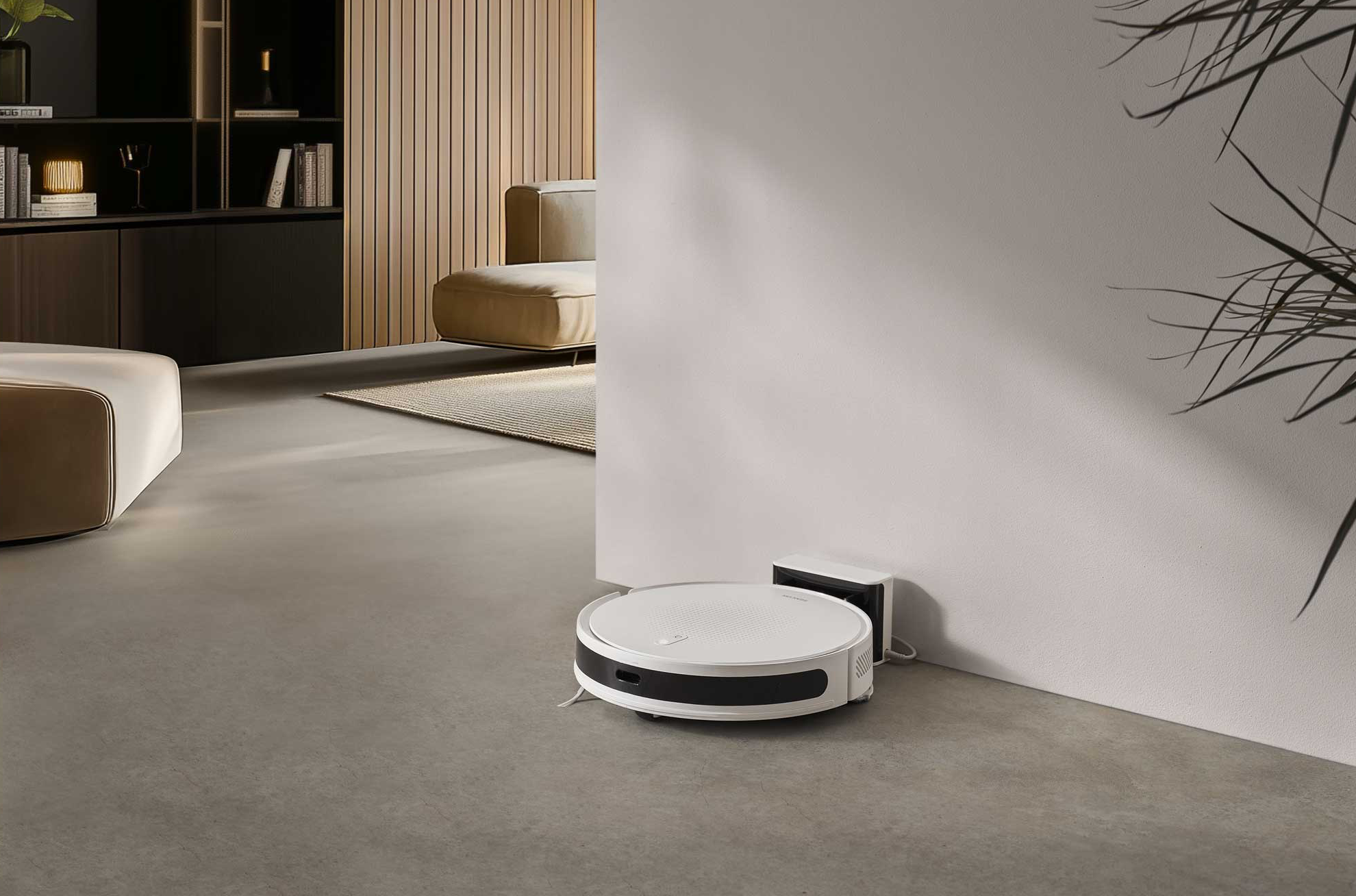 Egy fehér robotporszívó egy modern nappali fehér töltőállomásához csatlakozik.