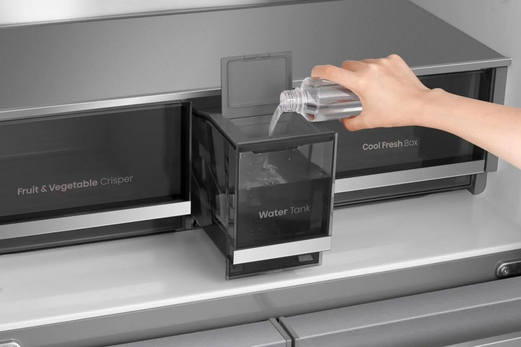 Eine Hand füllt einen transparenten Behälter mit Wasser in einem Kühlschrank.