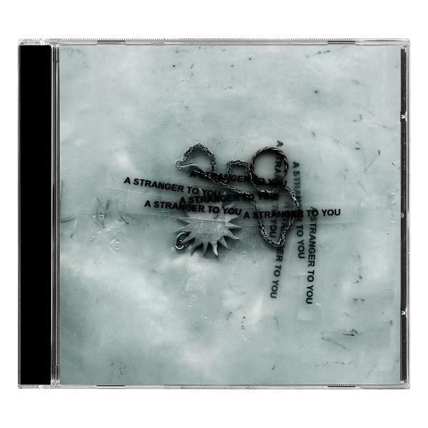 CD-Hülle mit Kette und Sonnensymbol auf blassem Hintergrund.