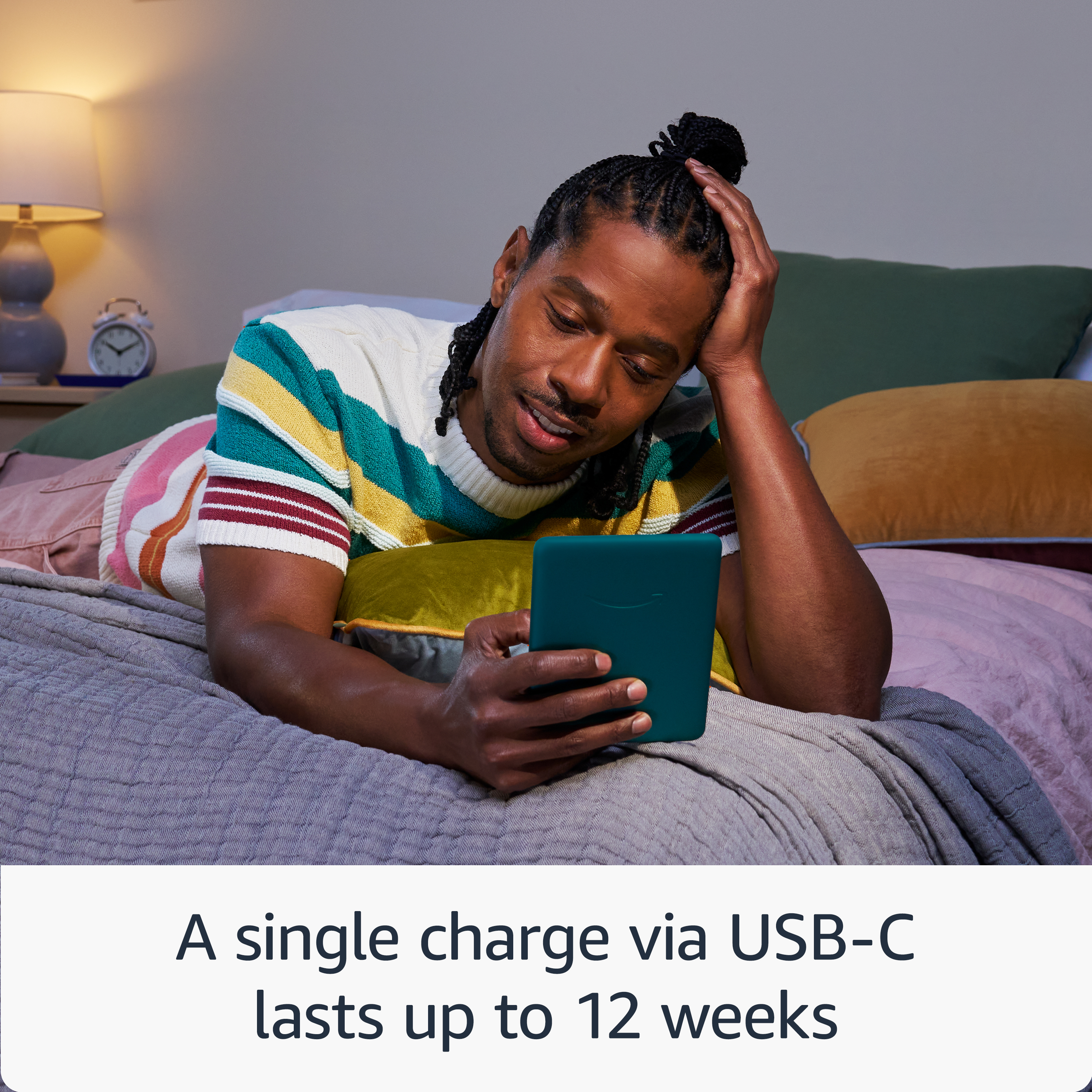 Uomo sdraiato sul letto legge e-reader. Vari cuscini e coperte.
