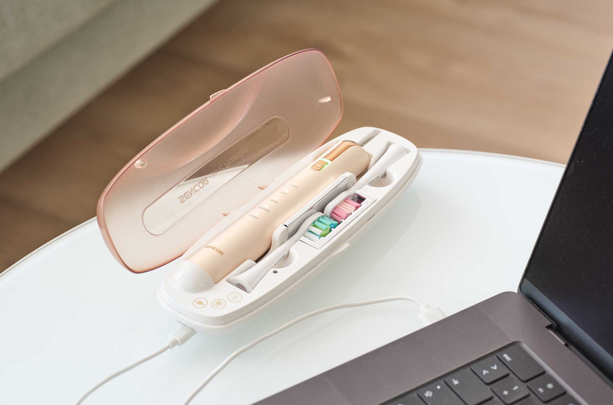 Elektromos fogkefe szett rózsaszín tokban, laptophoz csatlakoztatva.