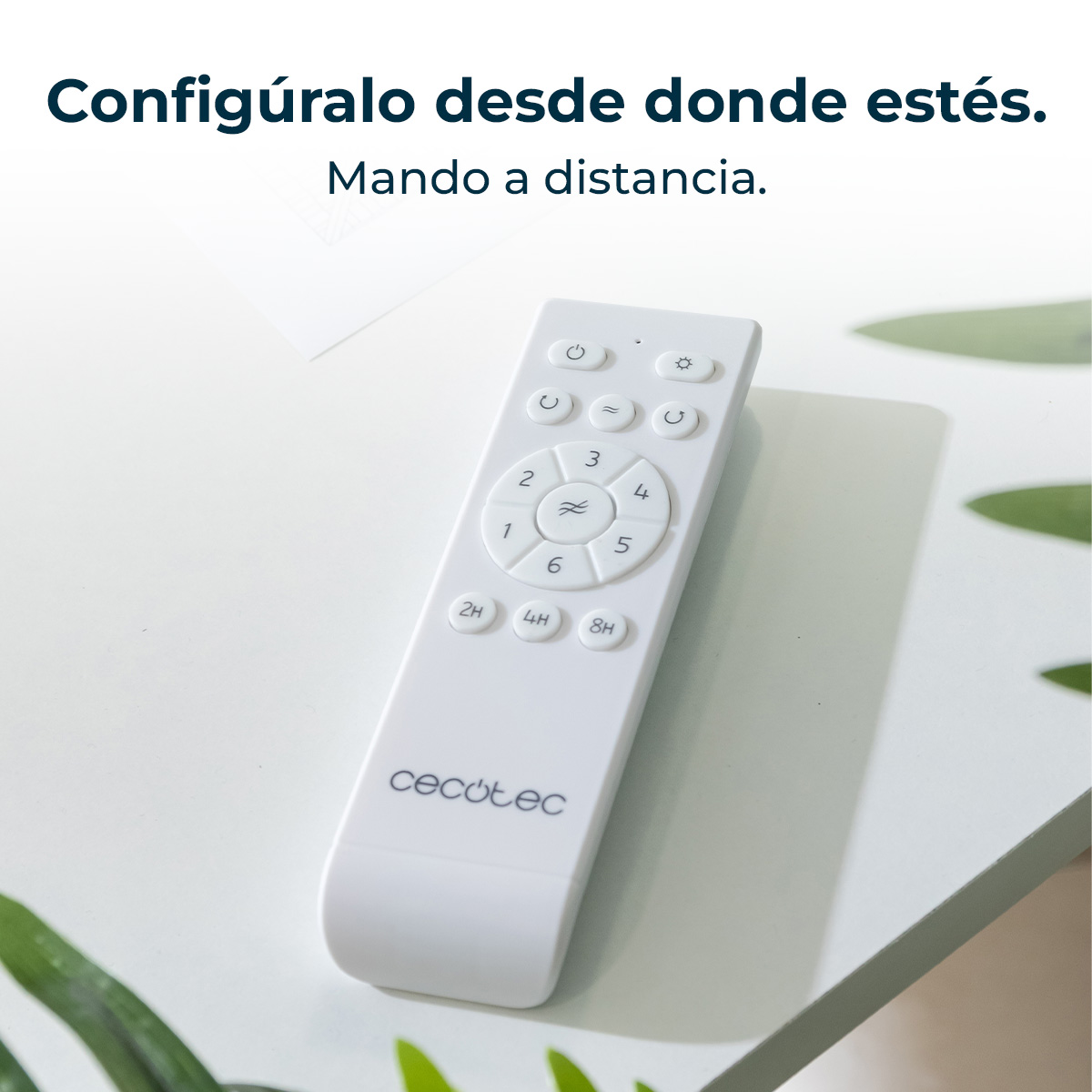Un mando a distancia blanco con botones y el logo de Cecotec sobre una mesa.