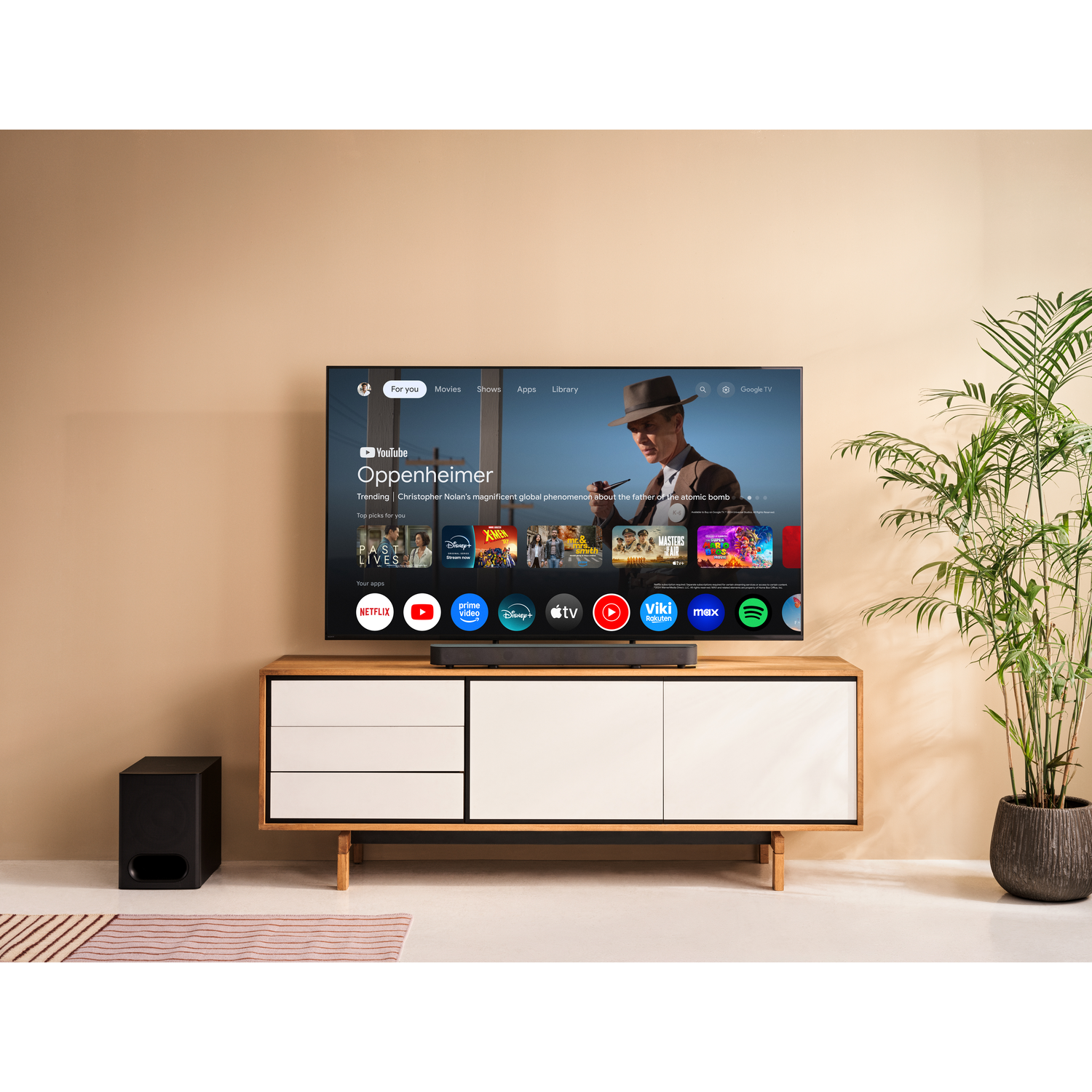A modern TV displays an app interface with movies and shows, next to a soundbar.