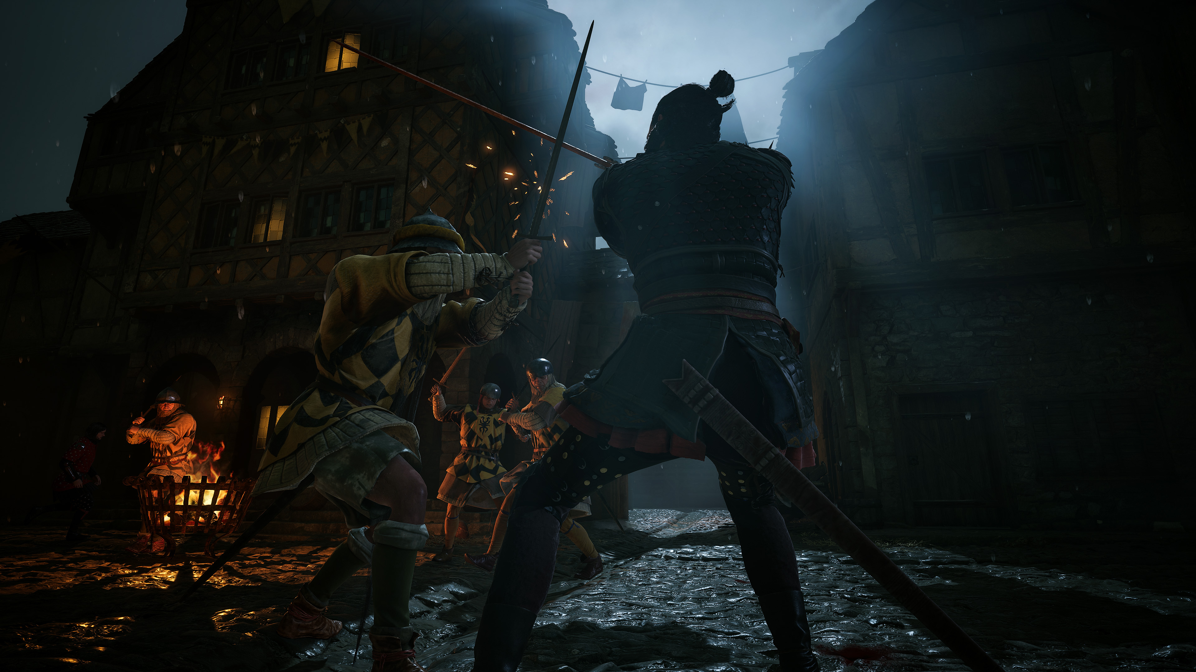 Rycerze walczą w deszczu przed średniowiecznym budynkiem. Kosz z ogniem daje światło.