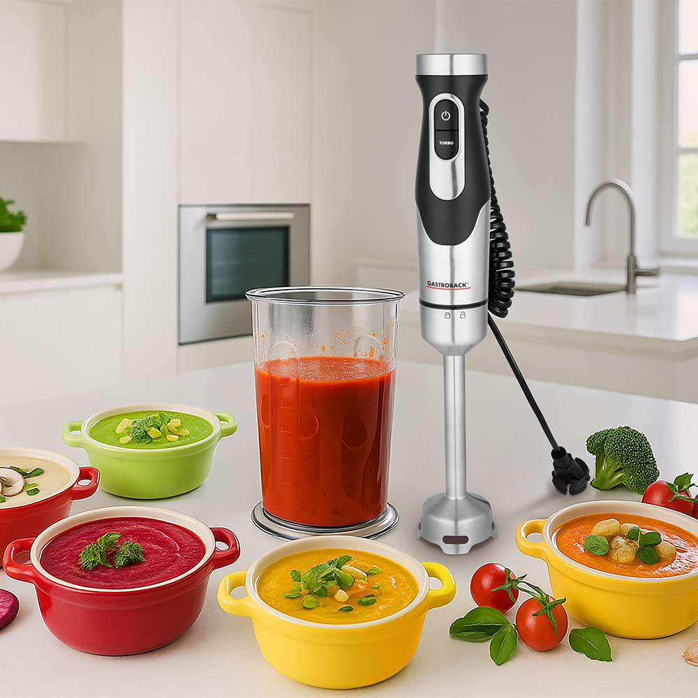 Ein Stabmixer steht neben Schüsseln mit Suppe und einem Messbecher voller Tomatensoße.