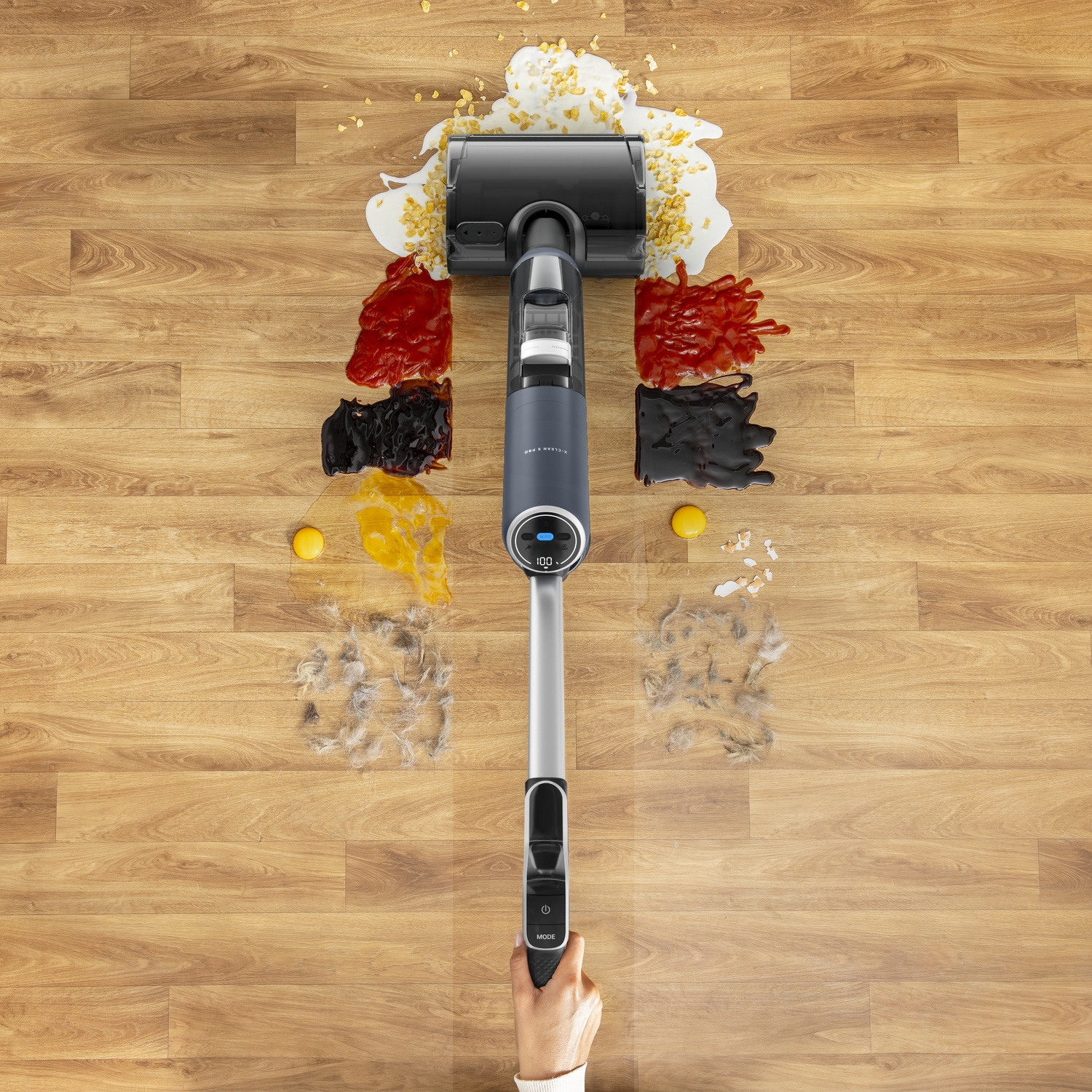 Vacuum cleaner cleans spills, crumbs, and hair on a wood floor.