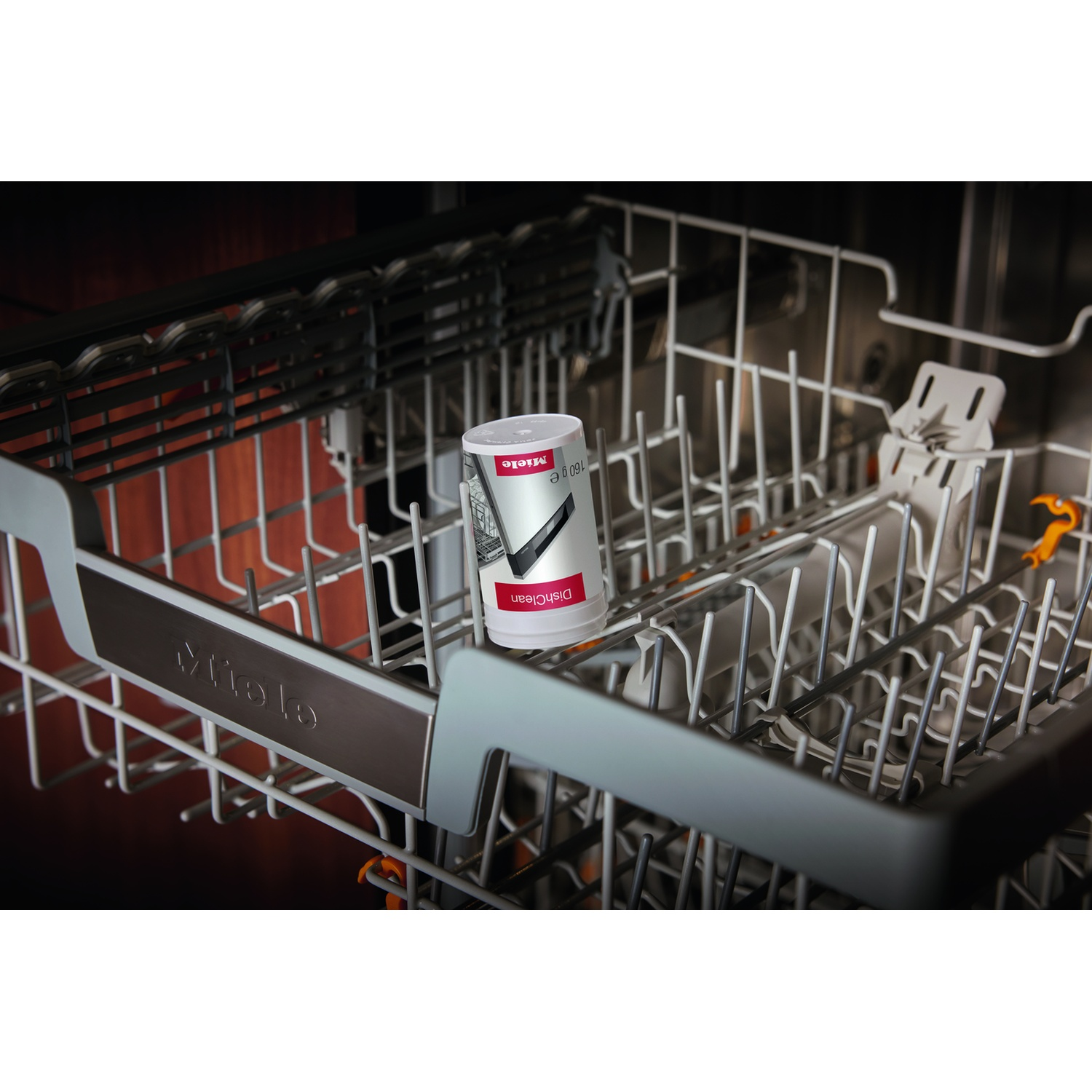 All'interno di una lavastoviglie, un prodotto Miele DishClean riposa sul cestello.