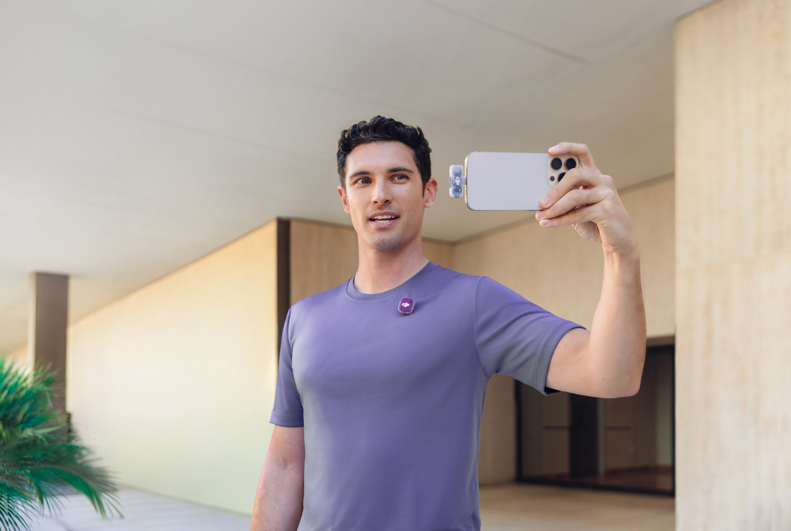 Homme en t-shirt violet tenant un smartphone pour prendre un selfie.
