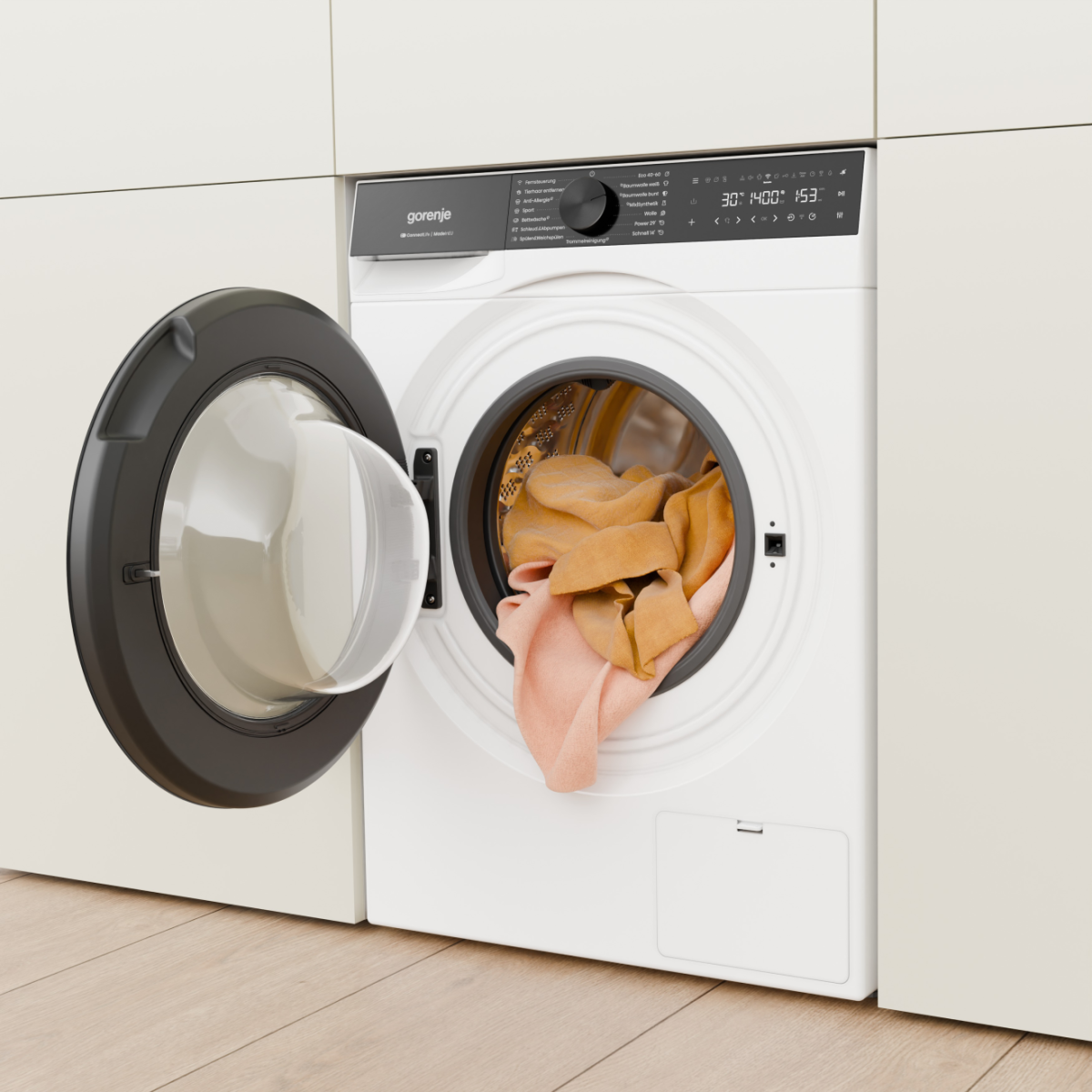 Eine weiße Gorenje-Waschmaschine mit geöffneter Tür, gefüllt mit orangefarbener und rosa Wäsche.