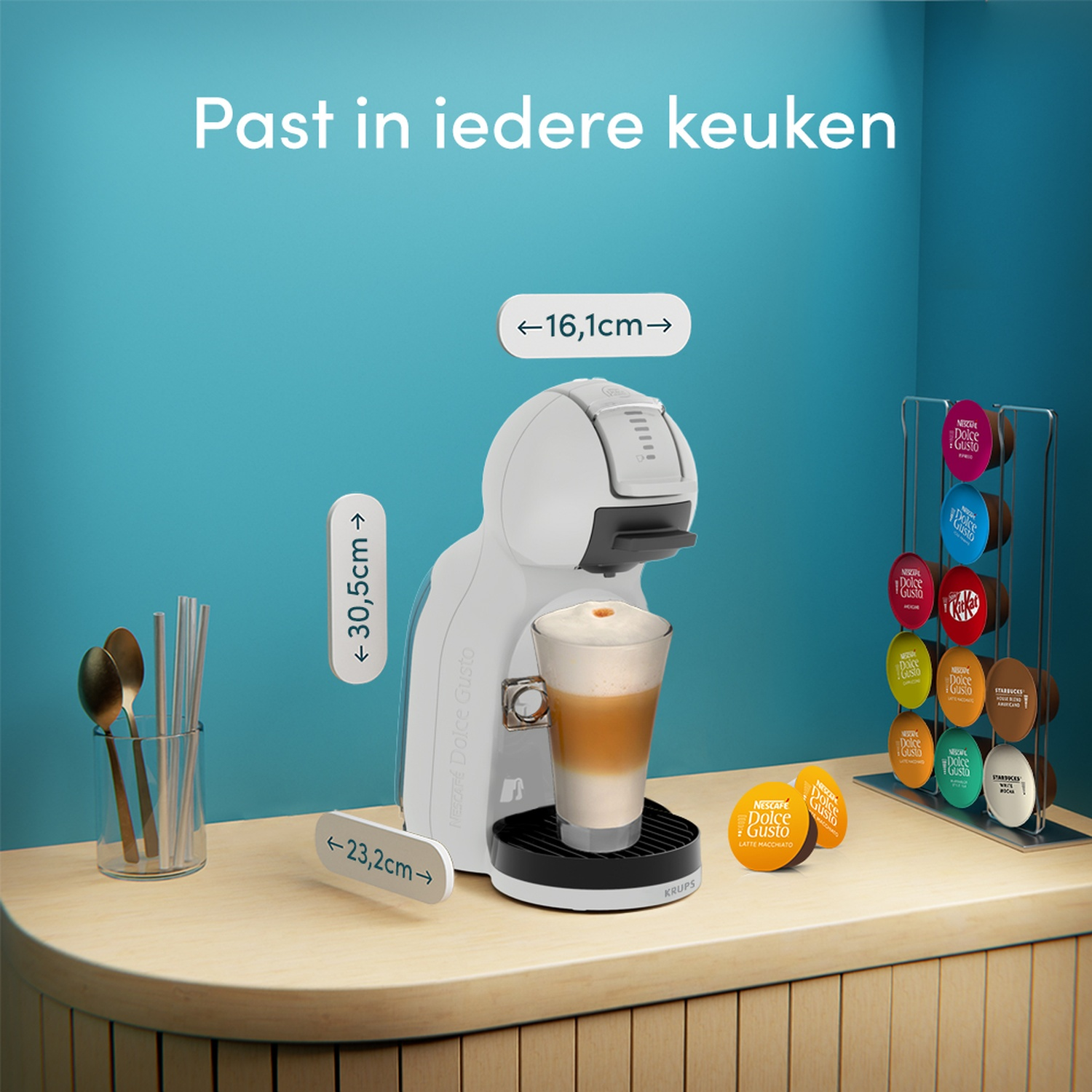 Een witte koffiemachine met een kop koffie en capsules ernaast.