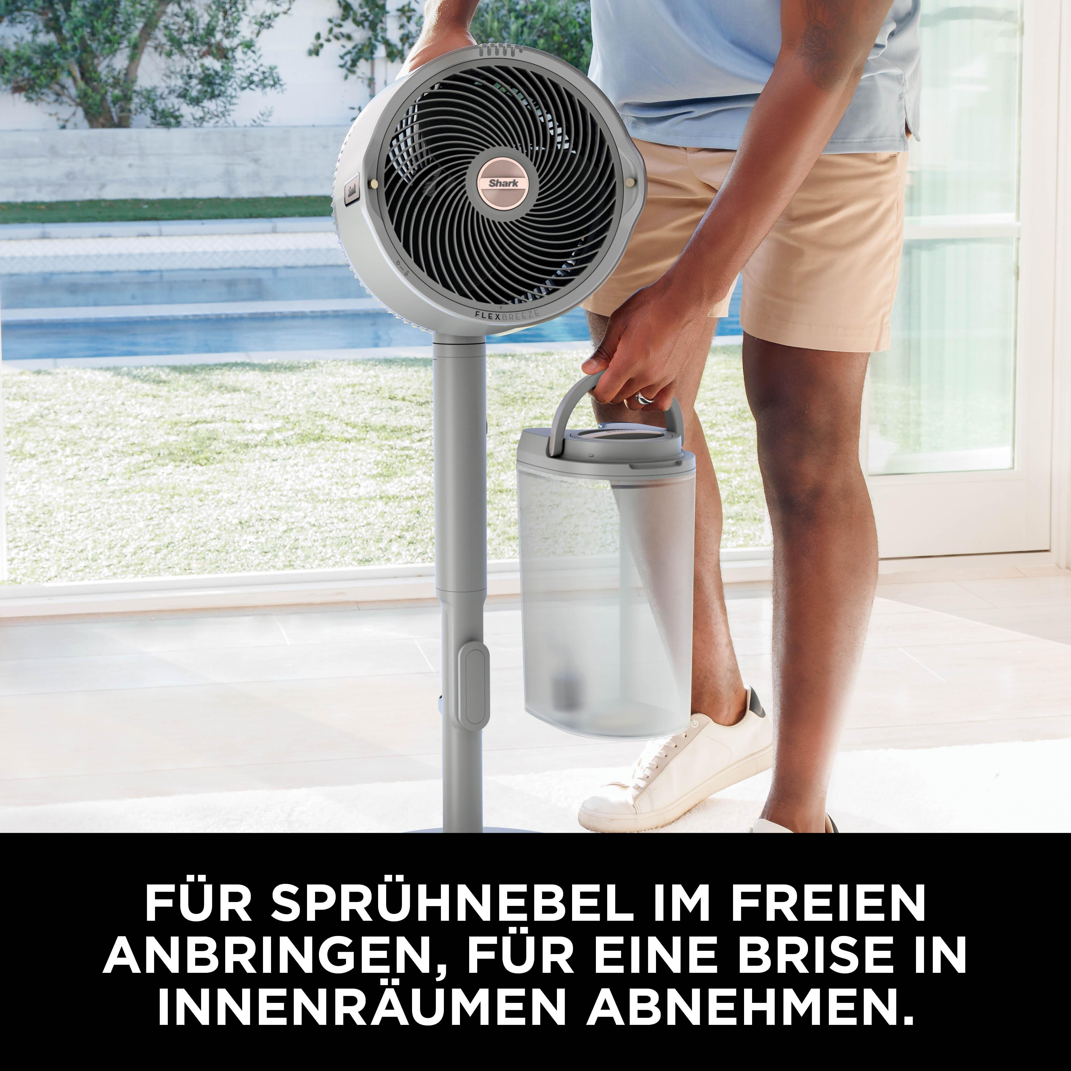 Mann hält einen tragbaren Ventilator mit Wassertank im Freien, neben einem Pool.
