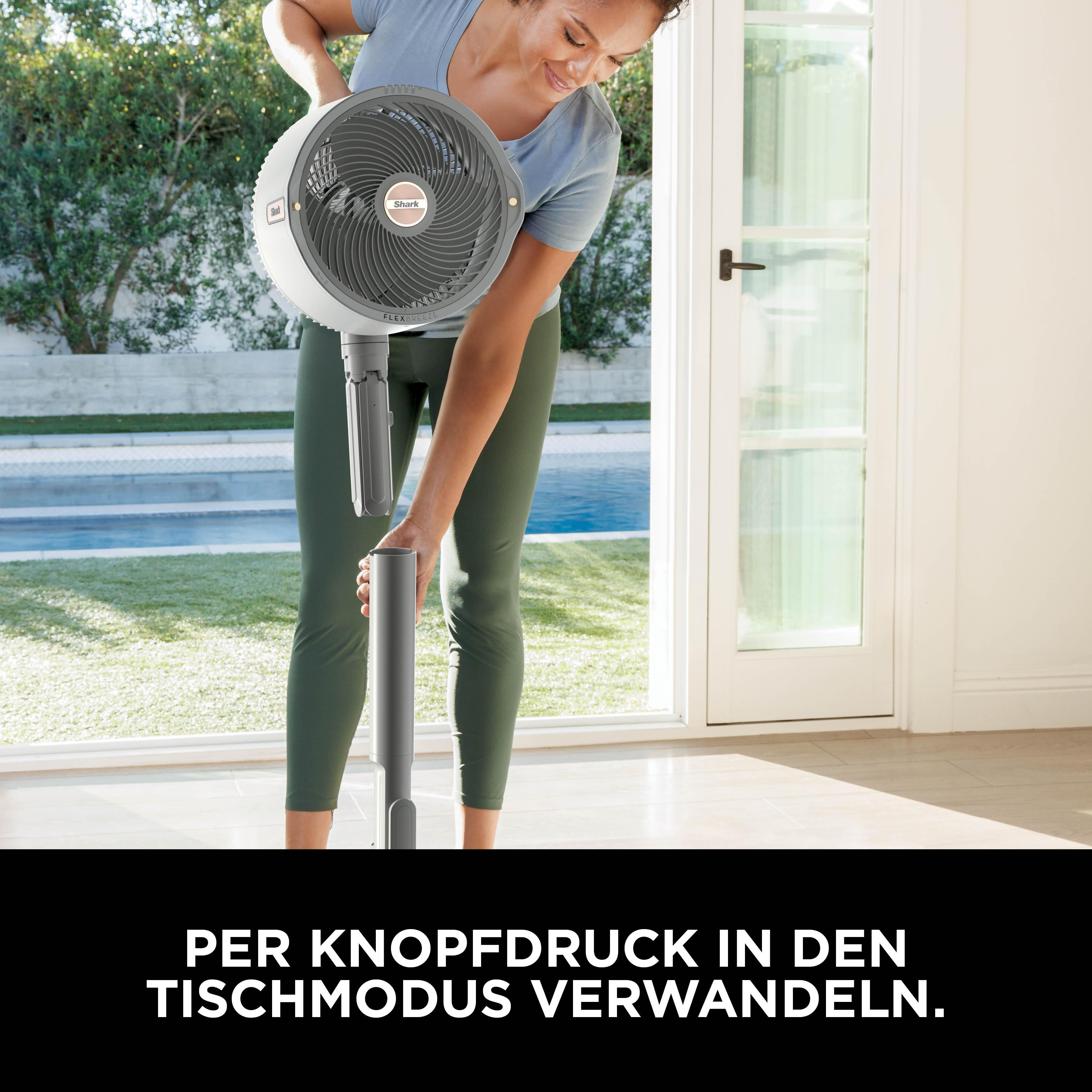 Frau richtet Ventilator auf einem Tisch auf. Draußen ist ein Pool sichtbar.