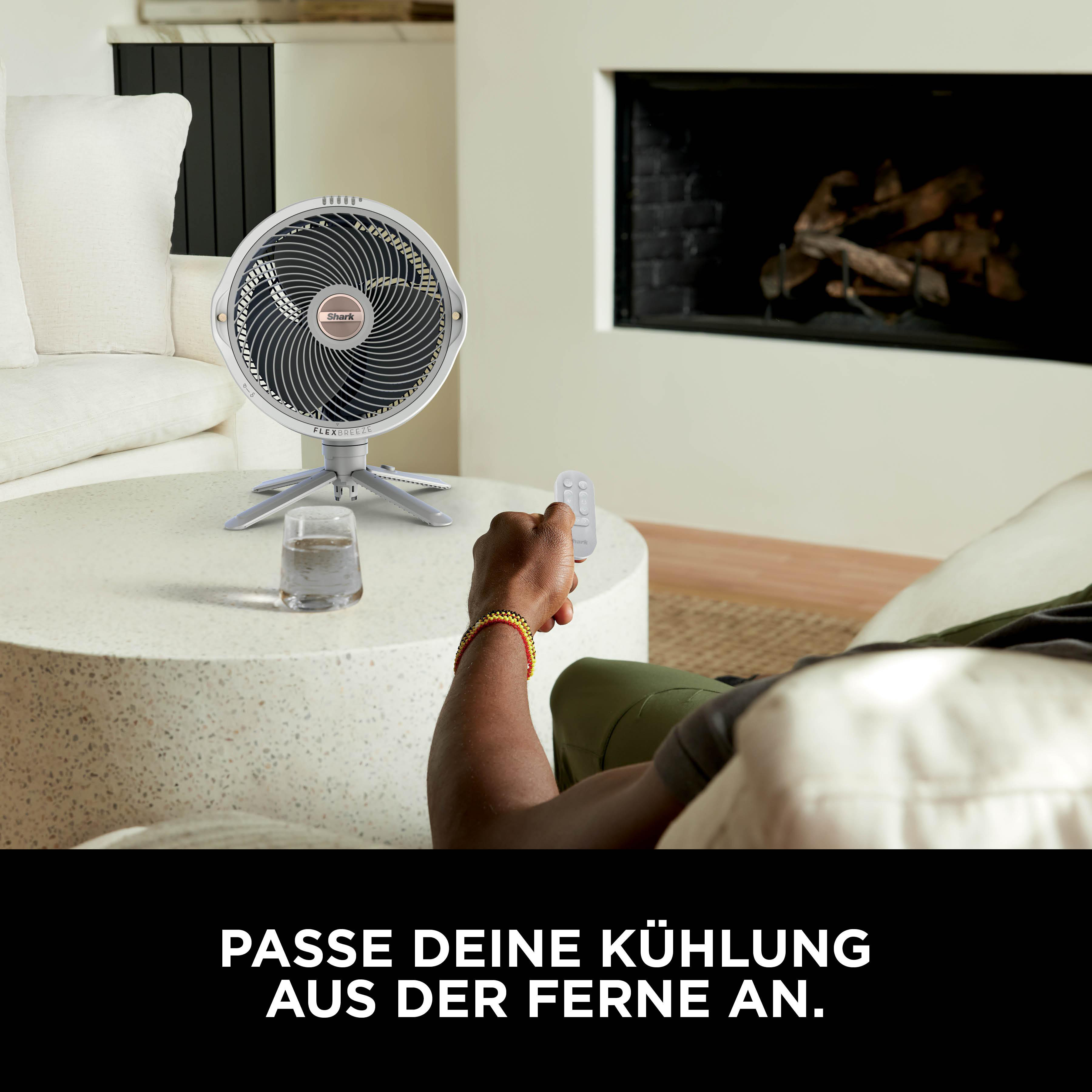 Mann hält Fernbedienung vor Ventilator auf Couchtisch, Wohnzimmer.