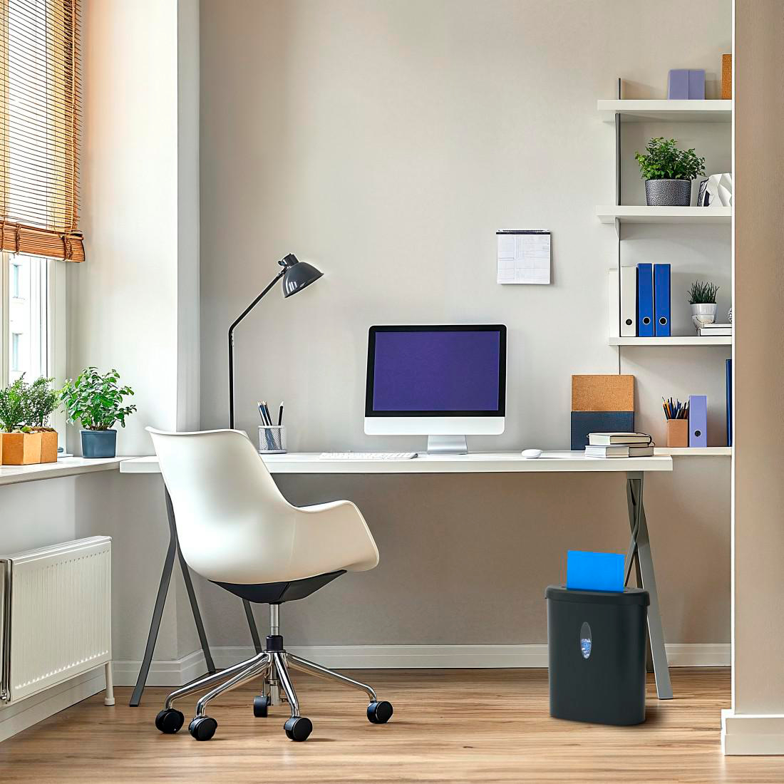 Ein Büro mit Schreibtisch, Computer, Stuhl, Aktenvernichter und Pflanzen.