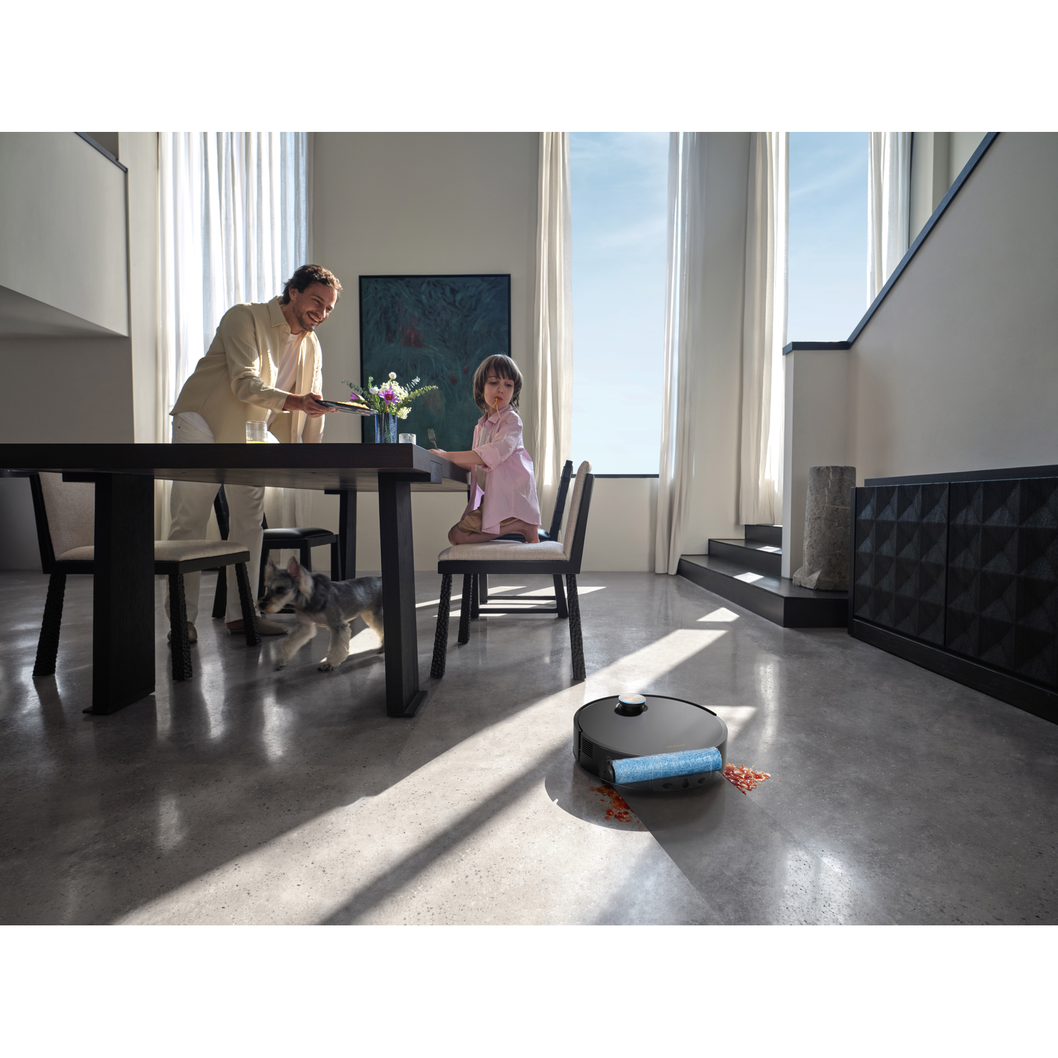 Een robotstofzuiger ruimt gemorst eten op terwijl een gezin aan tafel eet.