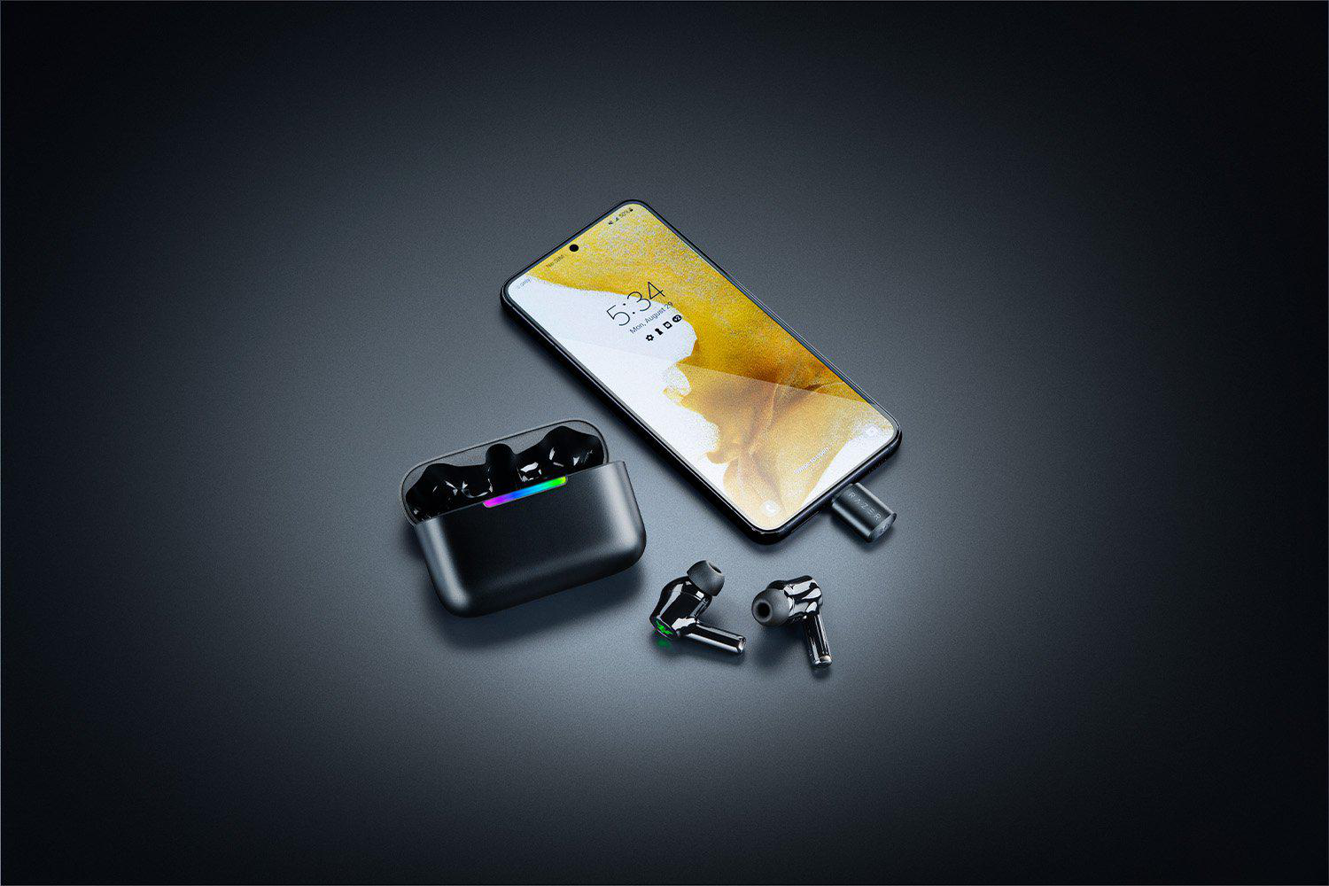 Schwarzes Smartphone mit Kopfhörern und Ladecase auf dunklem Hintergrund.