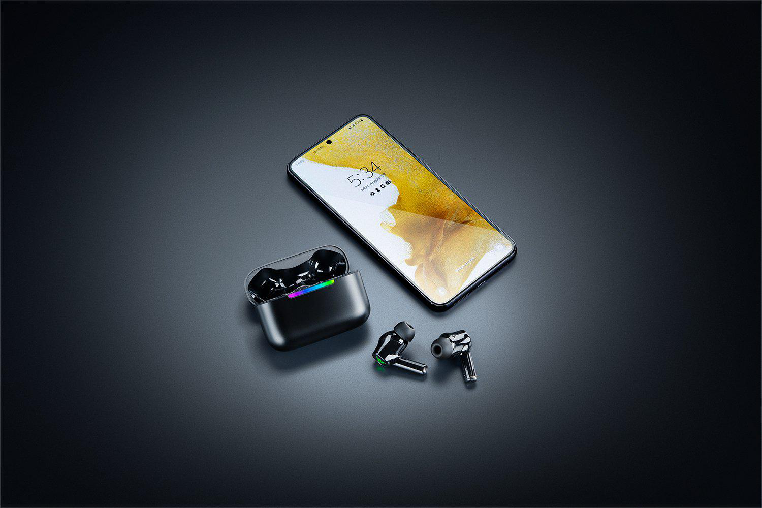 Ein Smartphone liegt neben einem schwarzen Ladecase mit leuchtenden Ohrhörern.