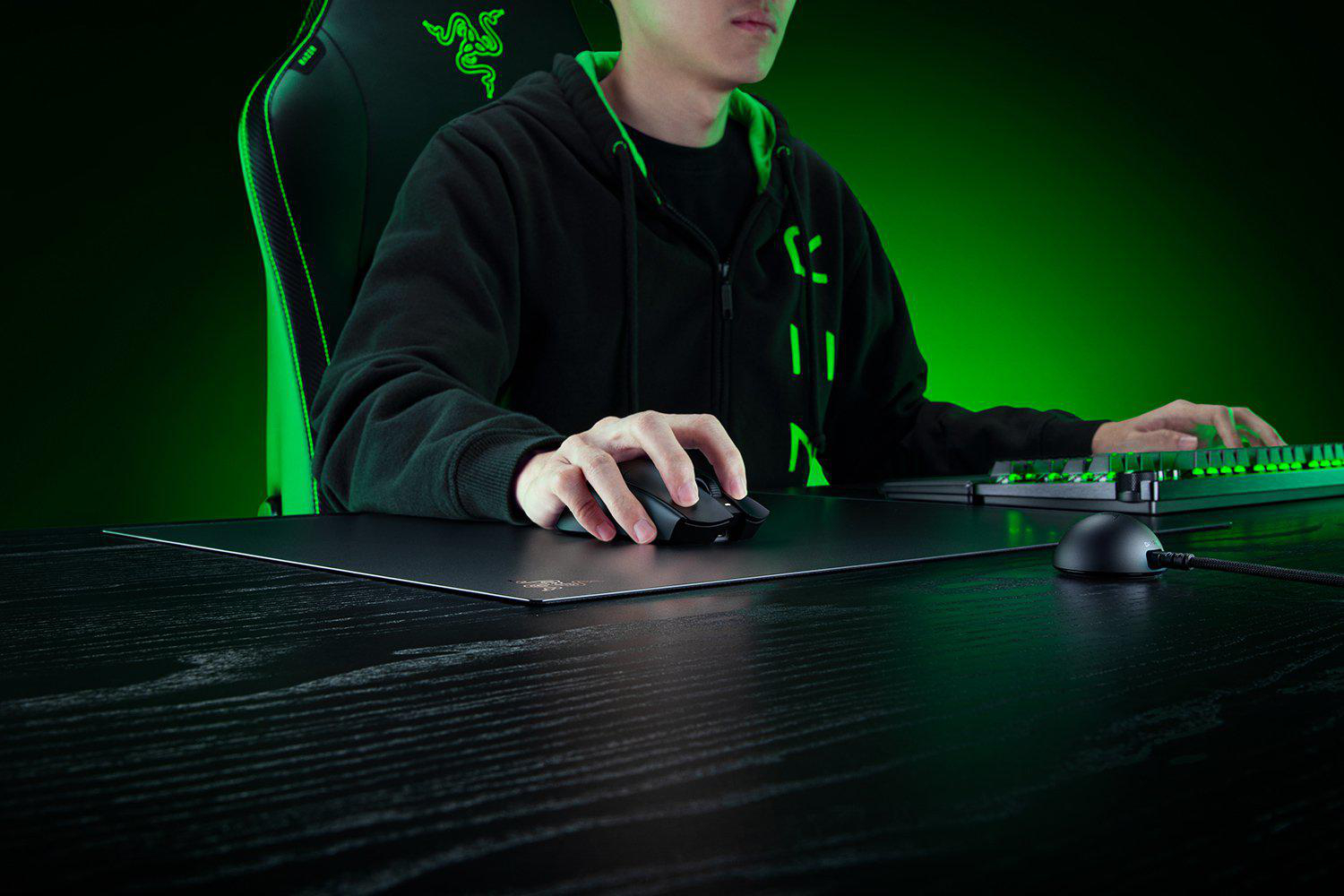 Person spielt mit Razer Maus und Tastatur vor grünem Hintergrund.