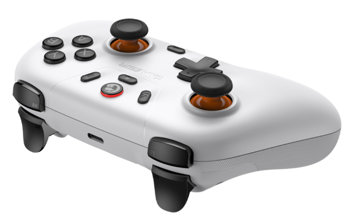 Biały kontroler do gier z czarnymi joystickami i pomarańczowymi akcentami.