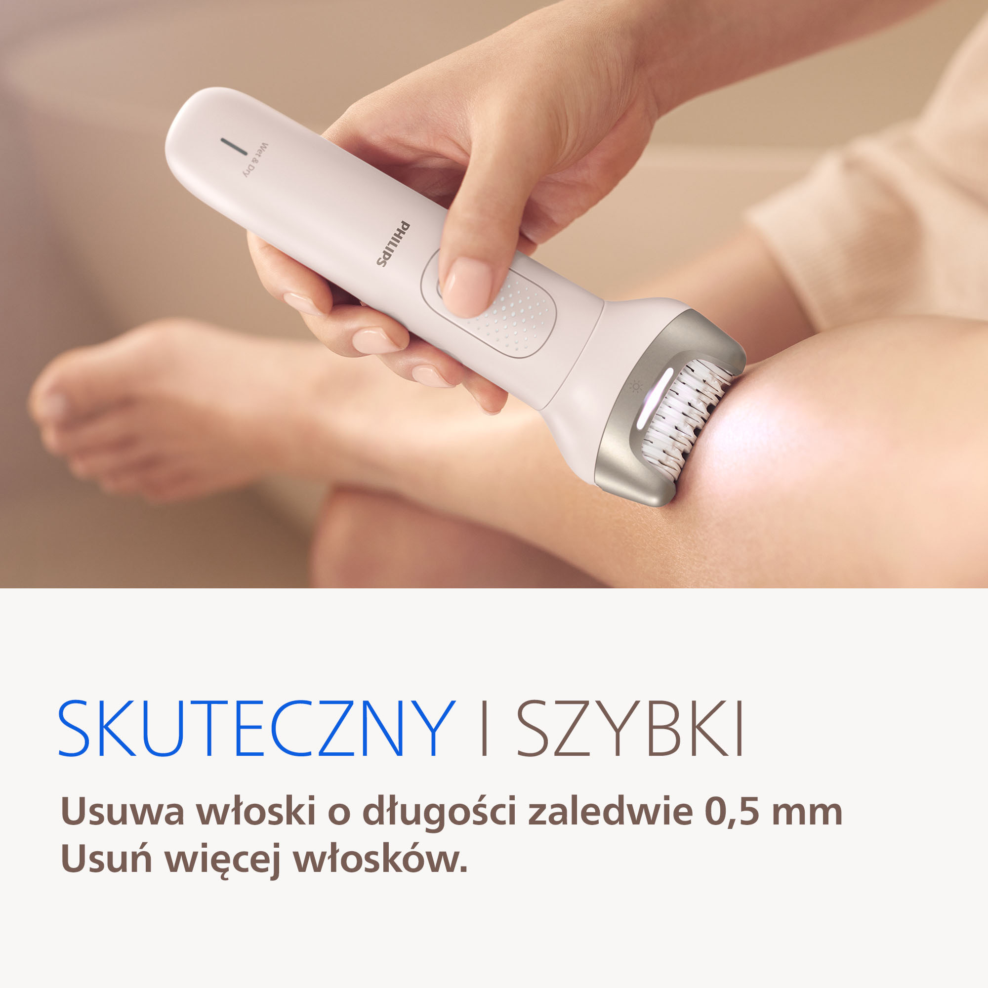 Dłoń używa białej depilatora Philips na nodze.