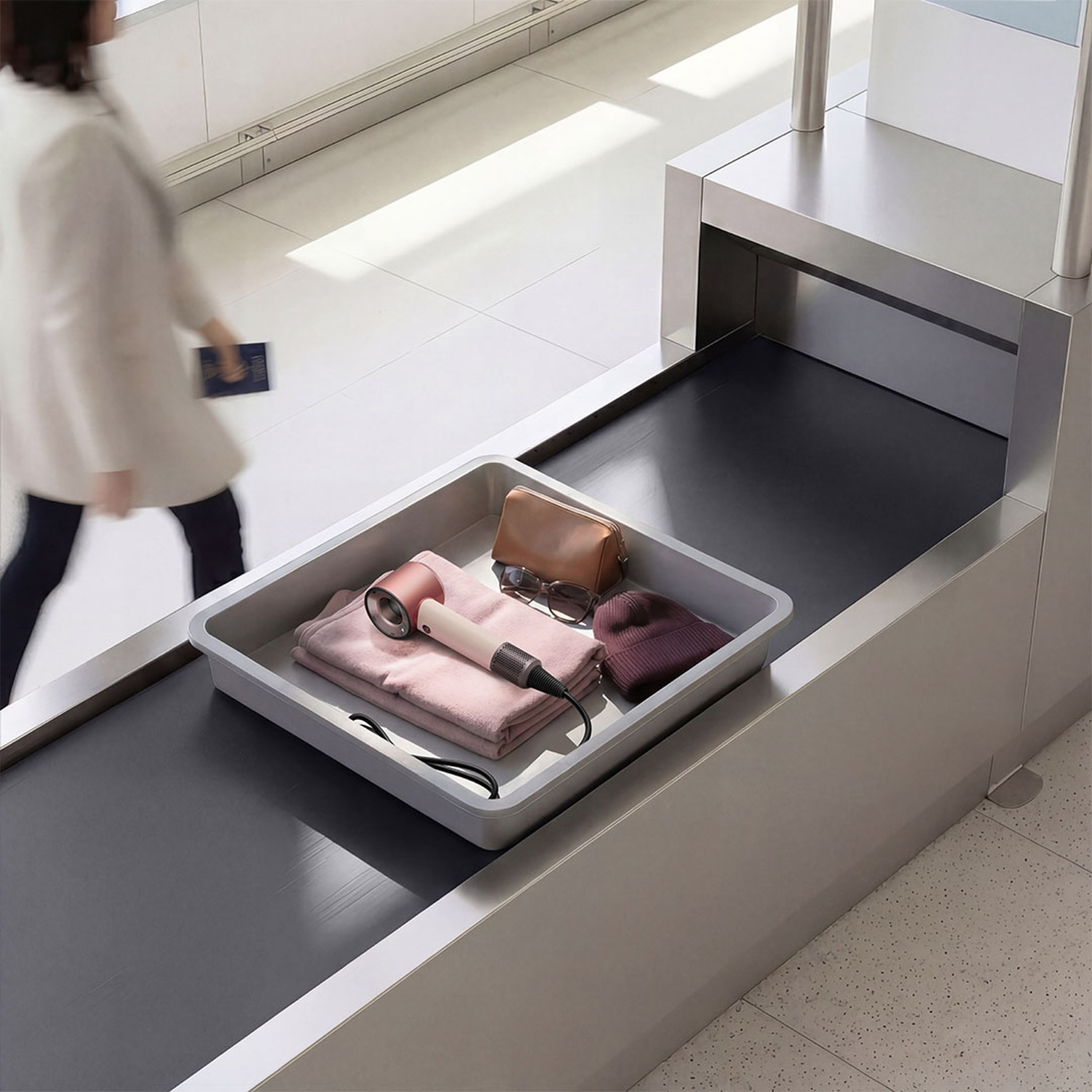 A tray of personal items on a conveyor belt before an X-ray scanner.