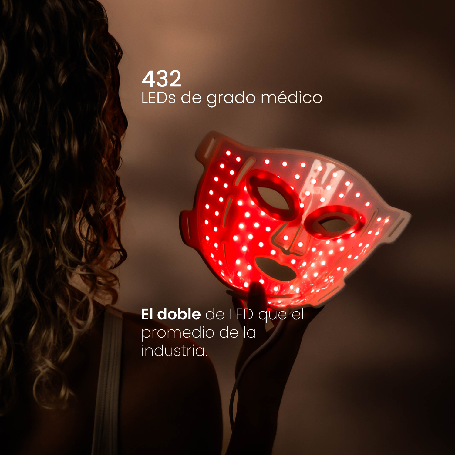 Una mujer sostiene una mascarilla LED roja brillante frente a su cara.