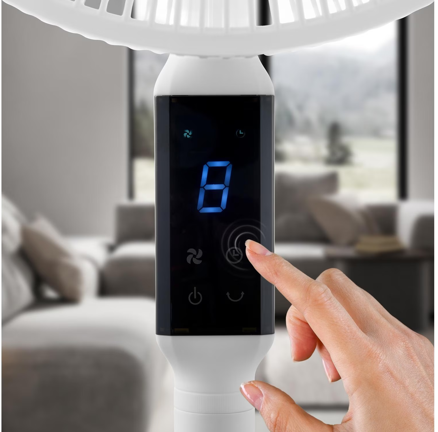 Eine Hand berührt das Display eines Ventilators mit blauer Anzeige und Symbolen.