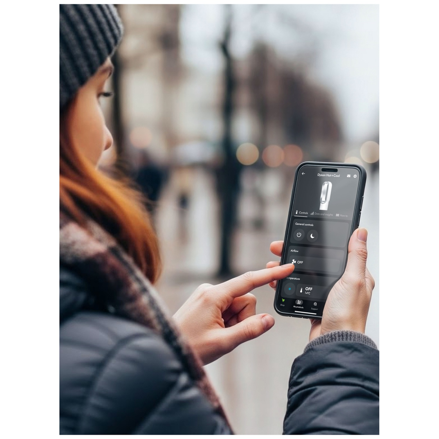 Persoon bedient Dyson Hot+Cool app op smartphone buiten.