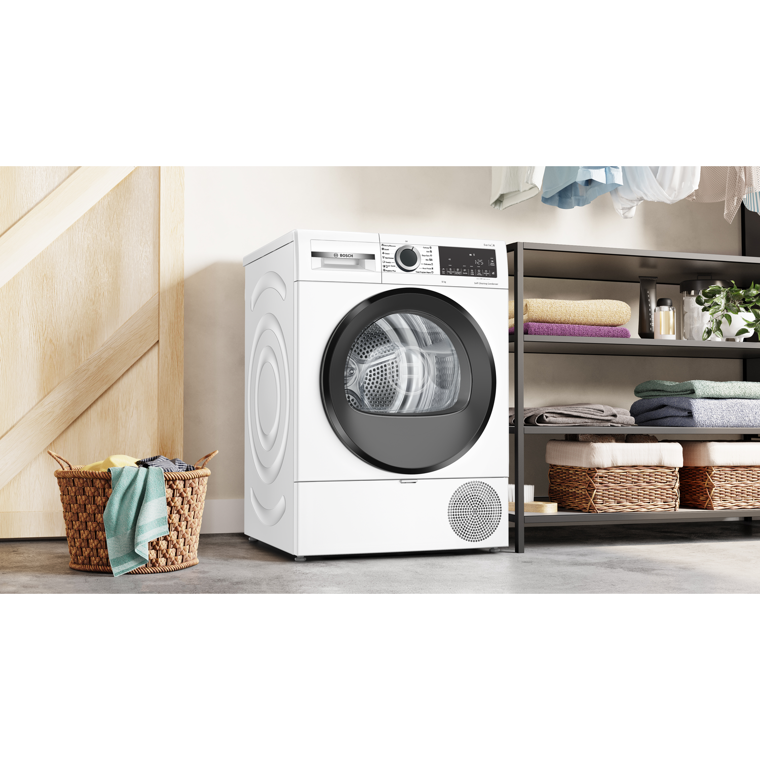 A white dryer sits next to a basket of laundry and towels on a shelf.